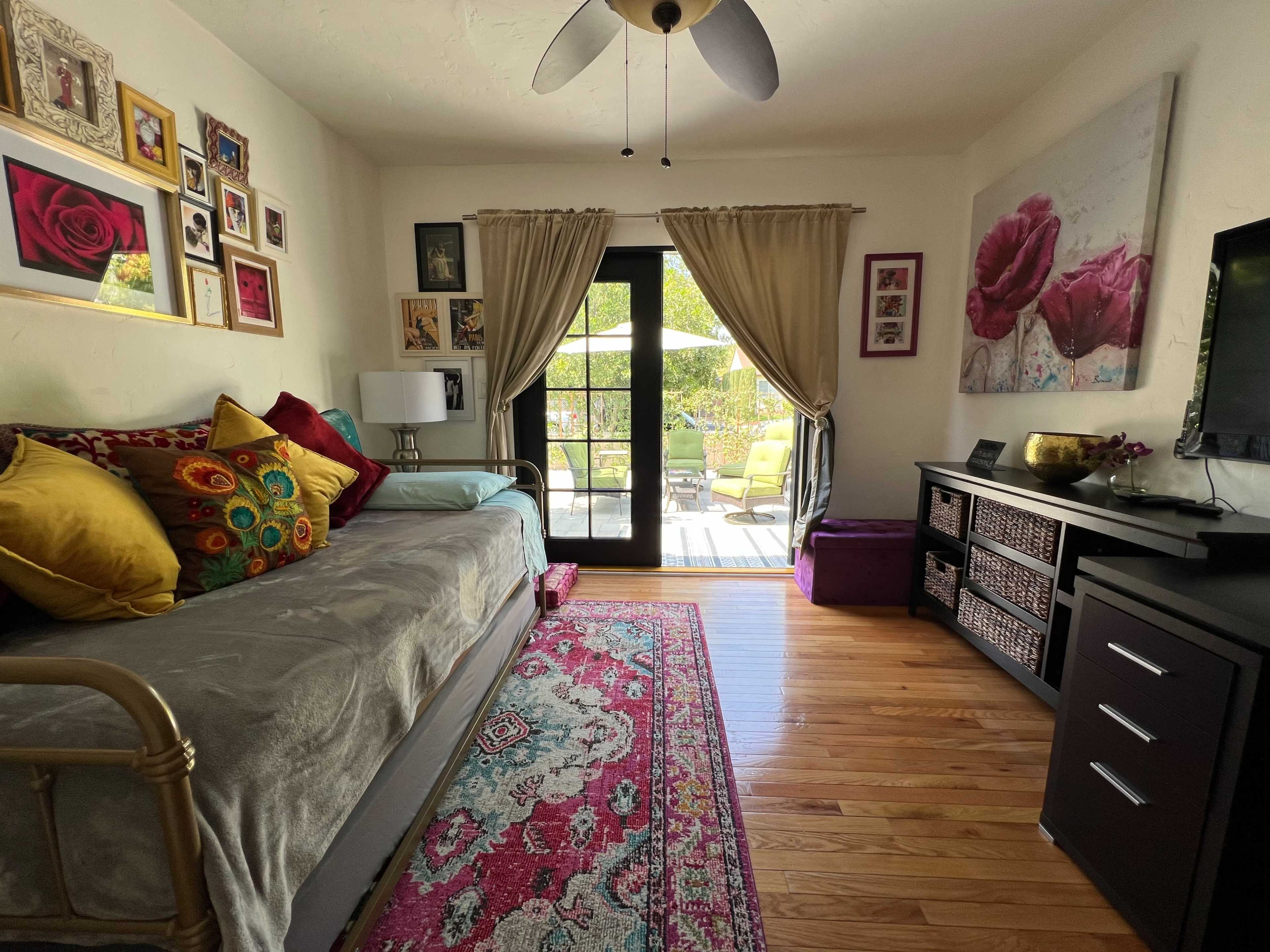 A cozy room with a bed, decorative pillows, a television, and large glass doors leading to a patio.