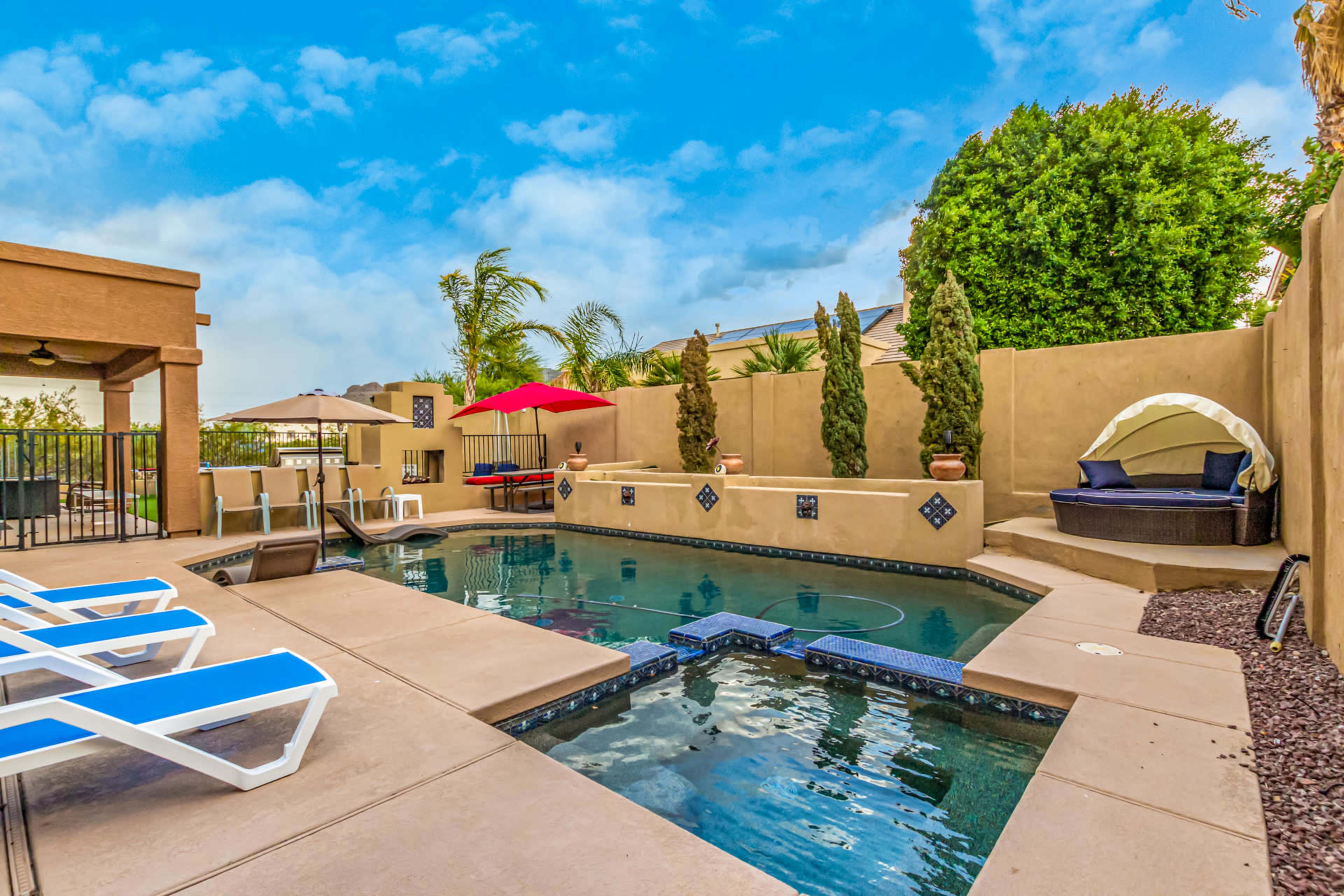 The image shows a backyard pool area featuring lounge chairs, a spa, and landscaped greenery.