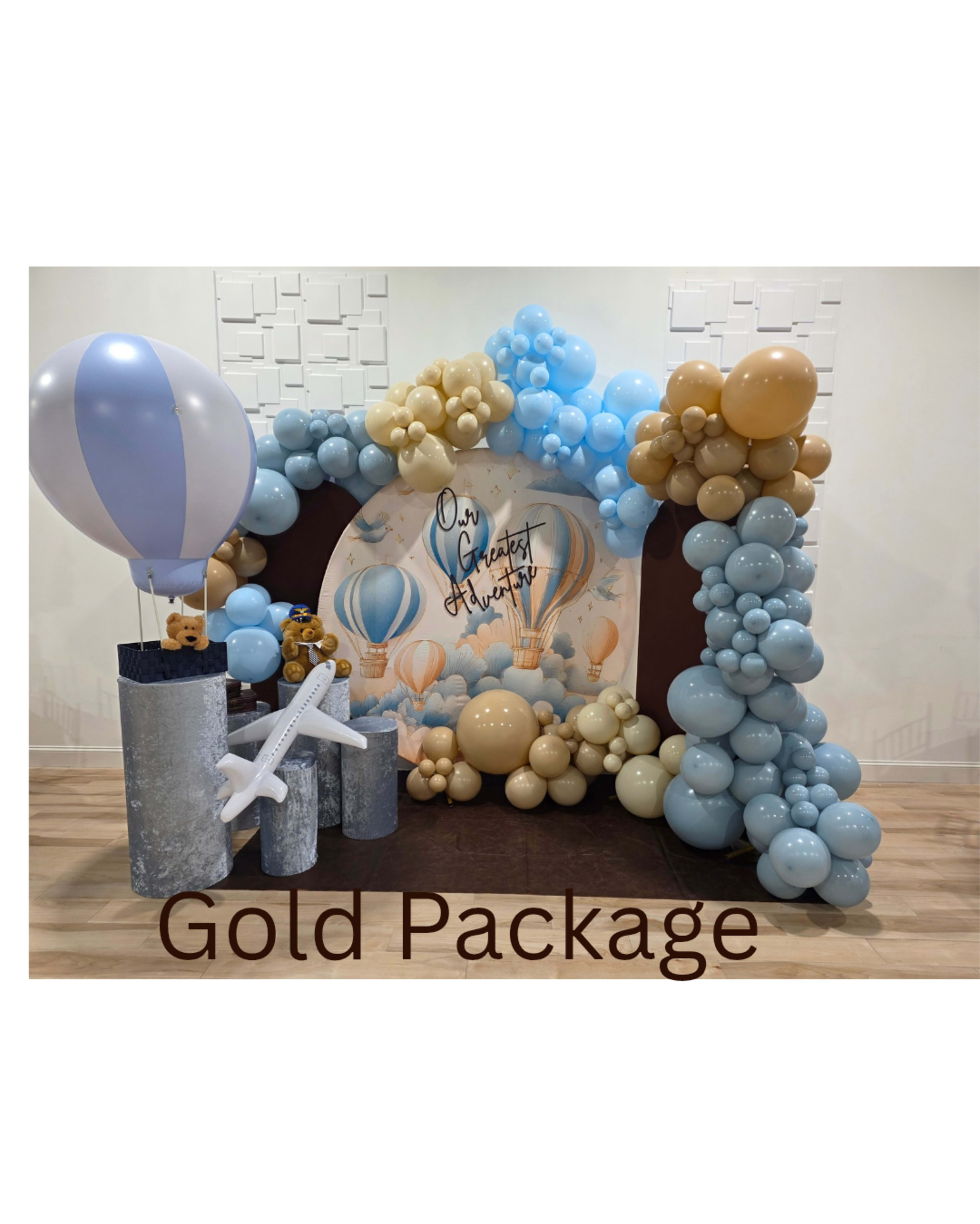 The image shows a decorative event setup featuring balloons in blue and gold colors, with a backdrop of hot air balloons and the words "Gold Package" prominently displayed.