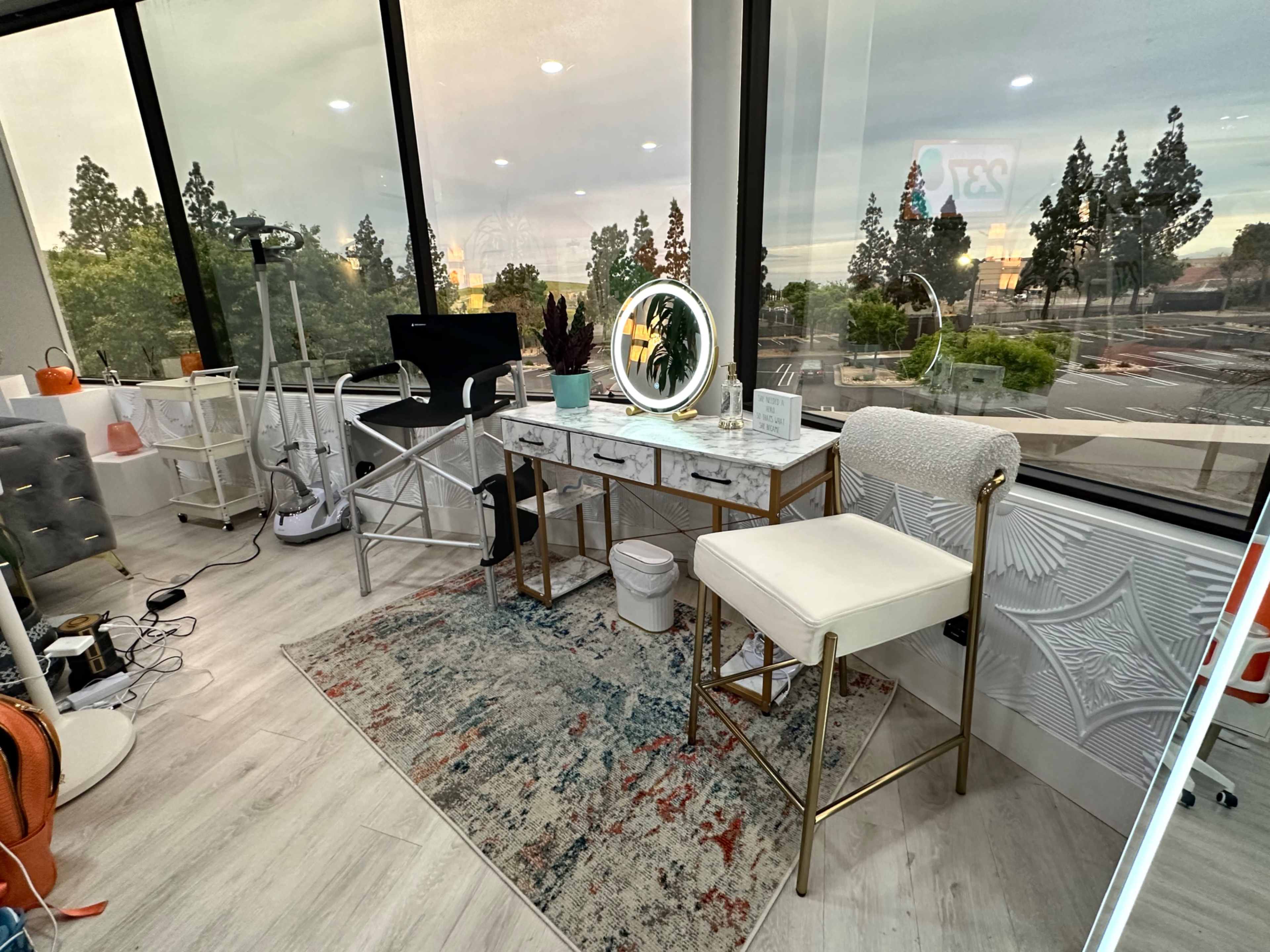 The image shows a modern workspace with a desk, a chair, and large windows overlooking a landscaped area.