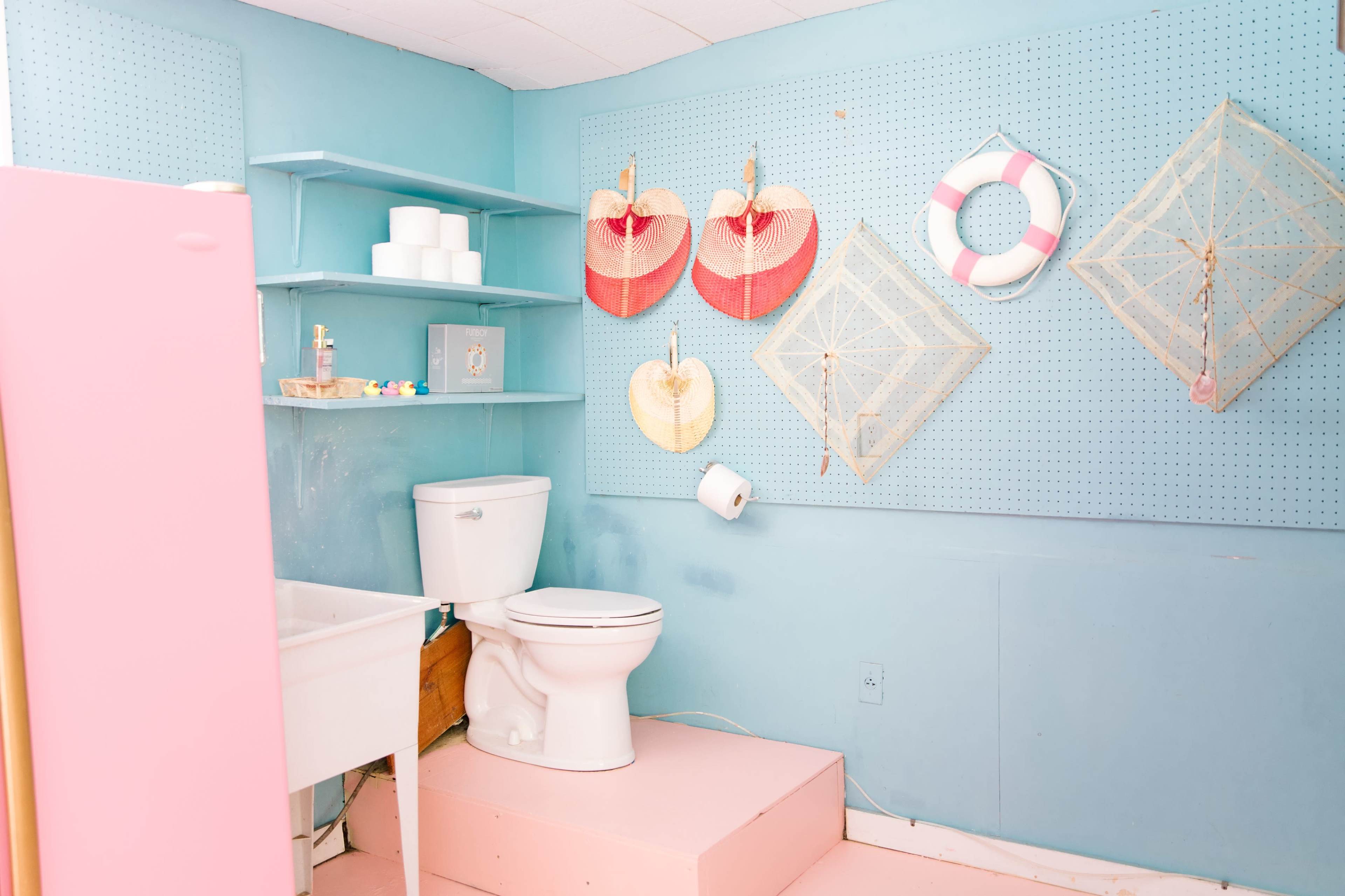 A brightly colored bathroom with a toilet, sink, and decorative items on the wall.