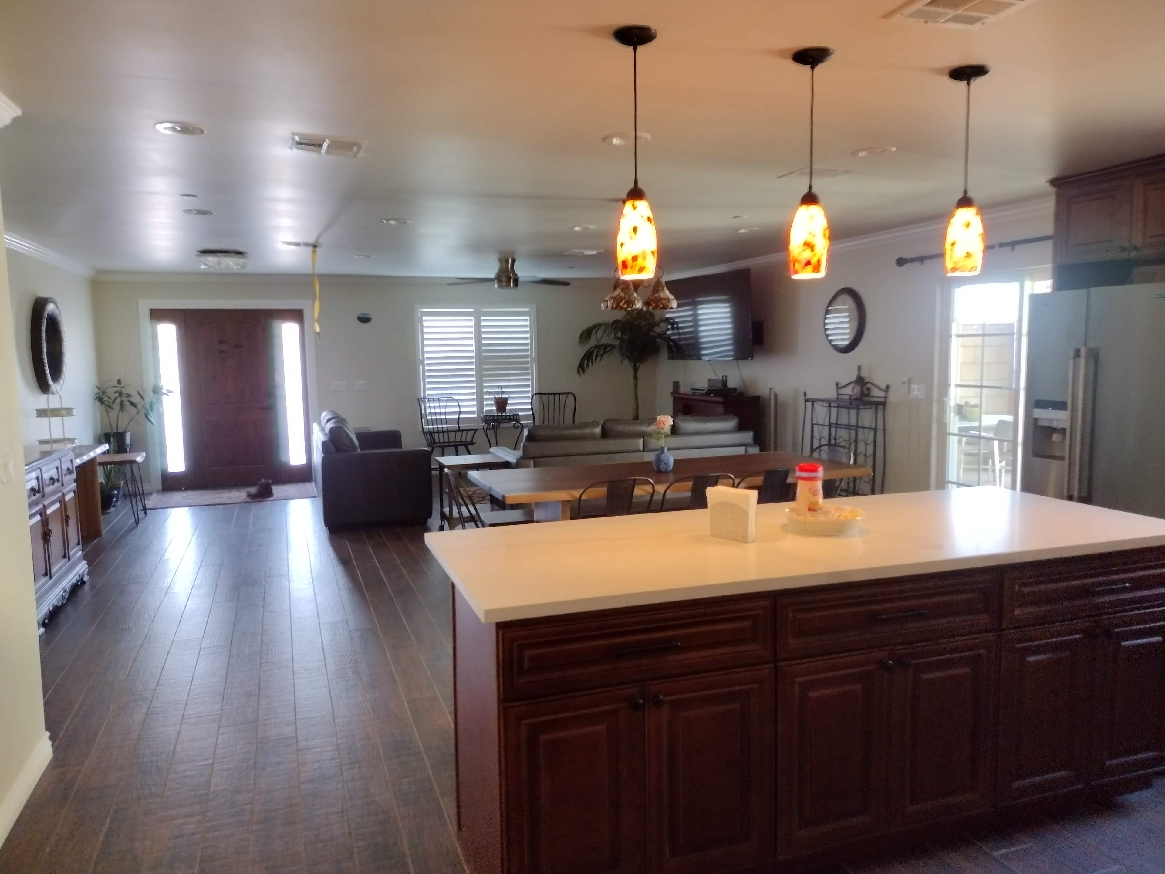 A spacious living and dining area with a kitchen featuring dark wooden cabinets, a large table, and multiple seating arrangements.