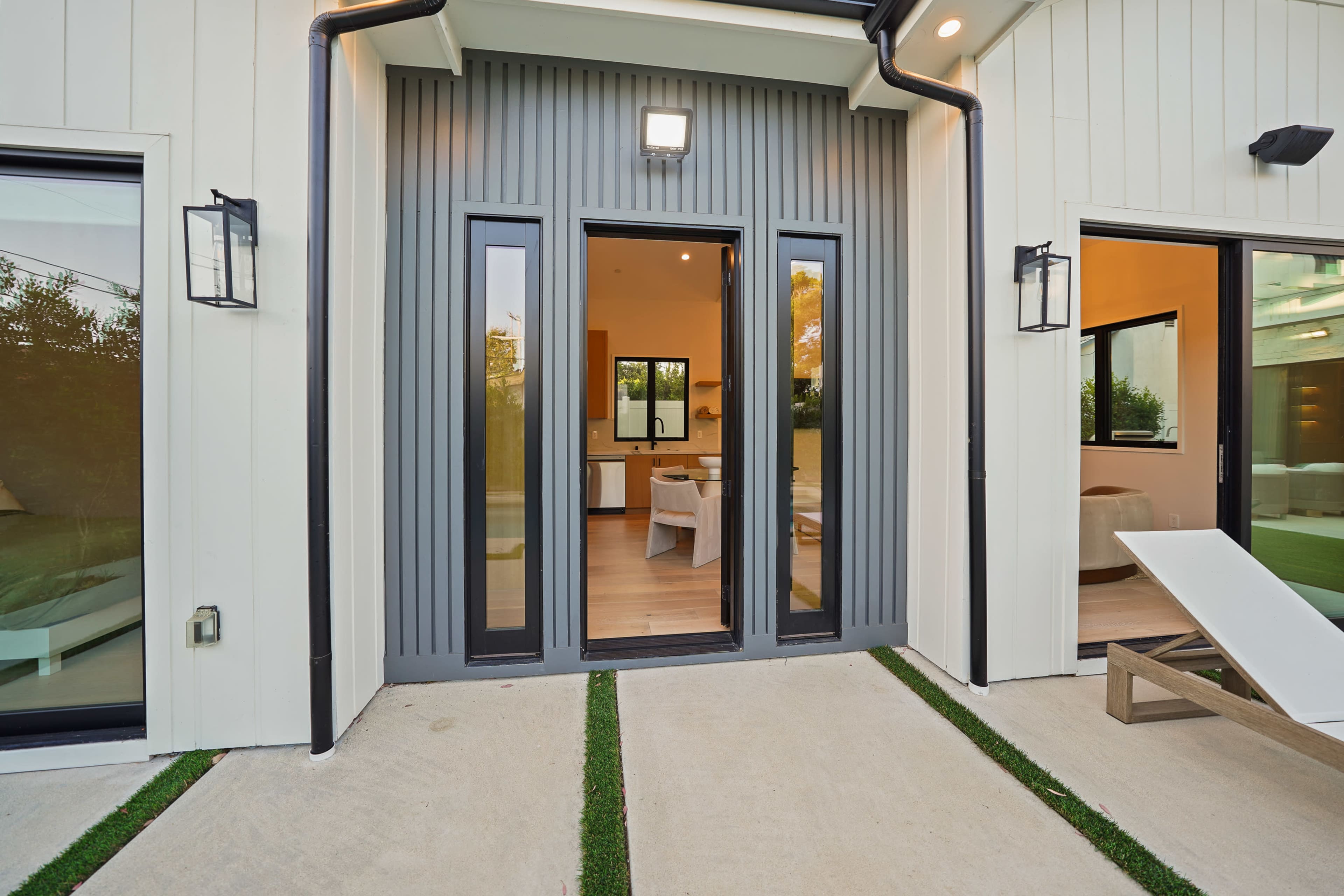 The image shows a modern entrance with double doors framed by windows on either side, leading into a well-lit interior space.