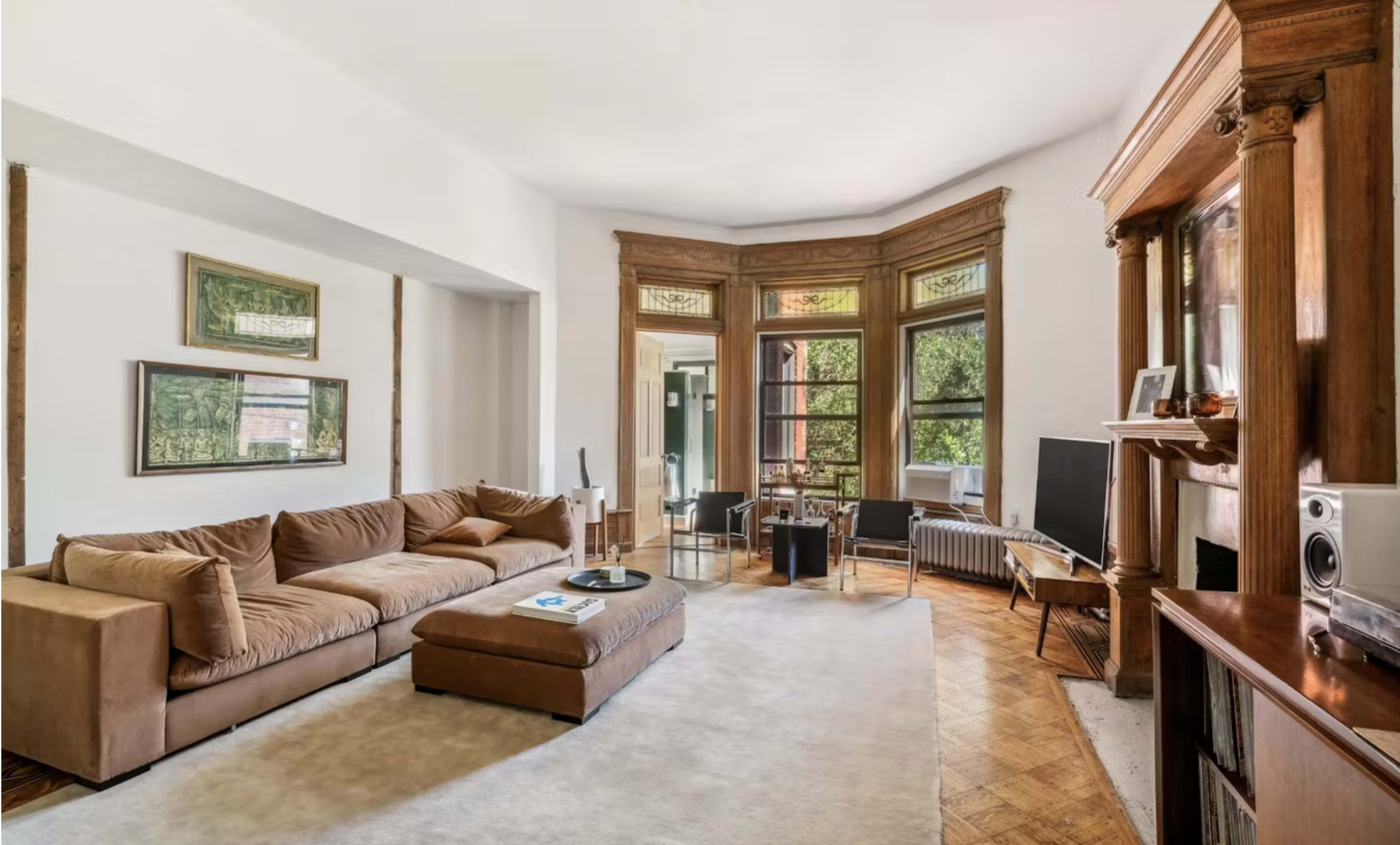The living room features a large sectional sofa, a coffee table, and a television, with windows allowing natural light to fill the space.