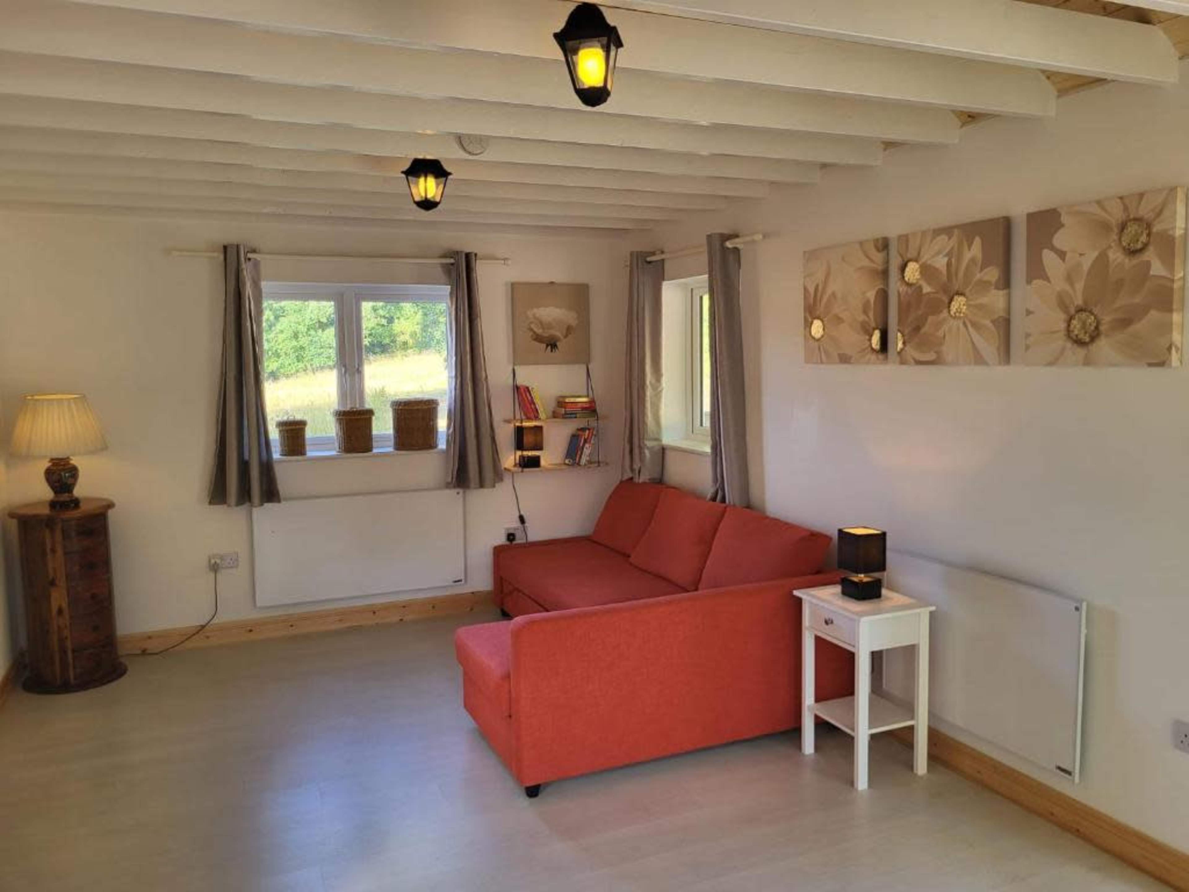 A cozy living room features an orange couch, a white side table, and decorative artwork on the walls, illuminated by pendant lights.