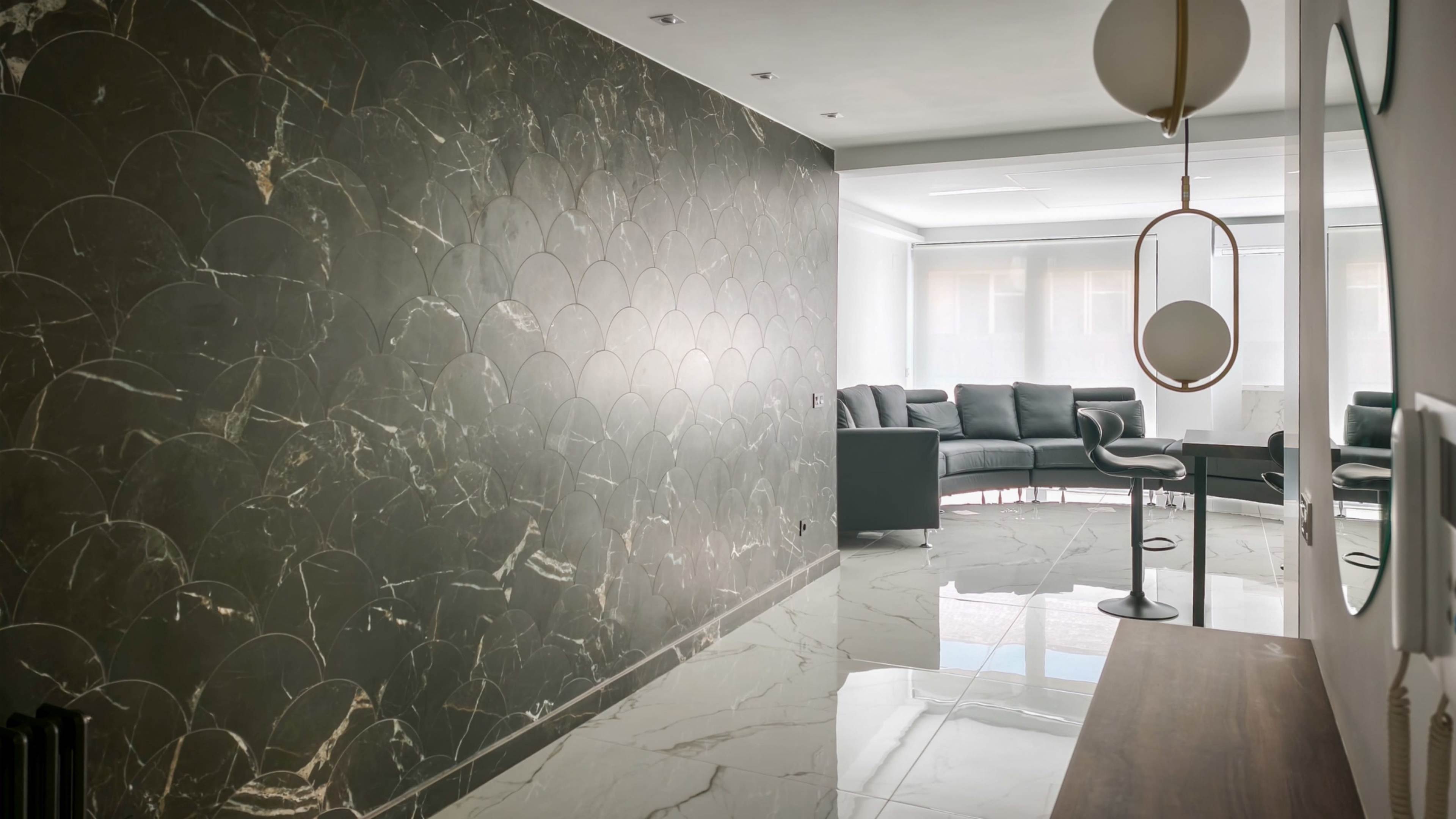 The image shows a modern interior with a marble-patterned wall, a sleek couch set in the corner, and glossy tiled flooring reflecting the light.