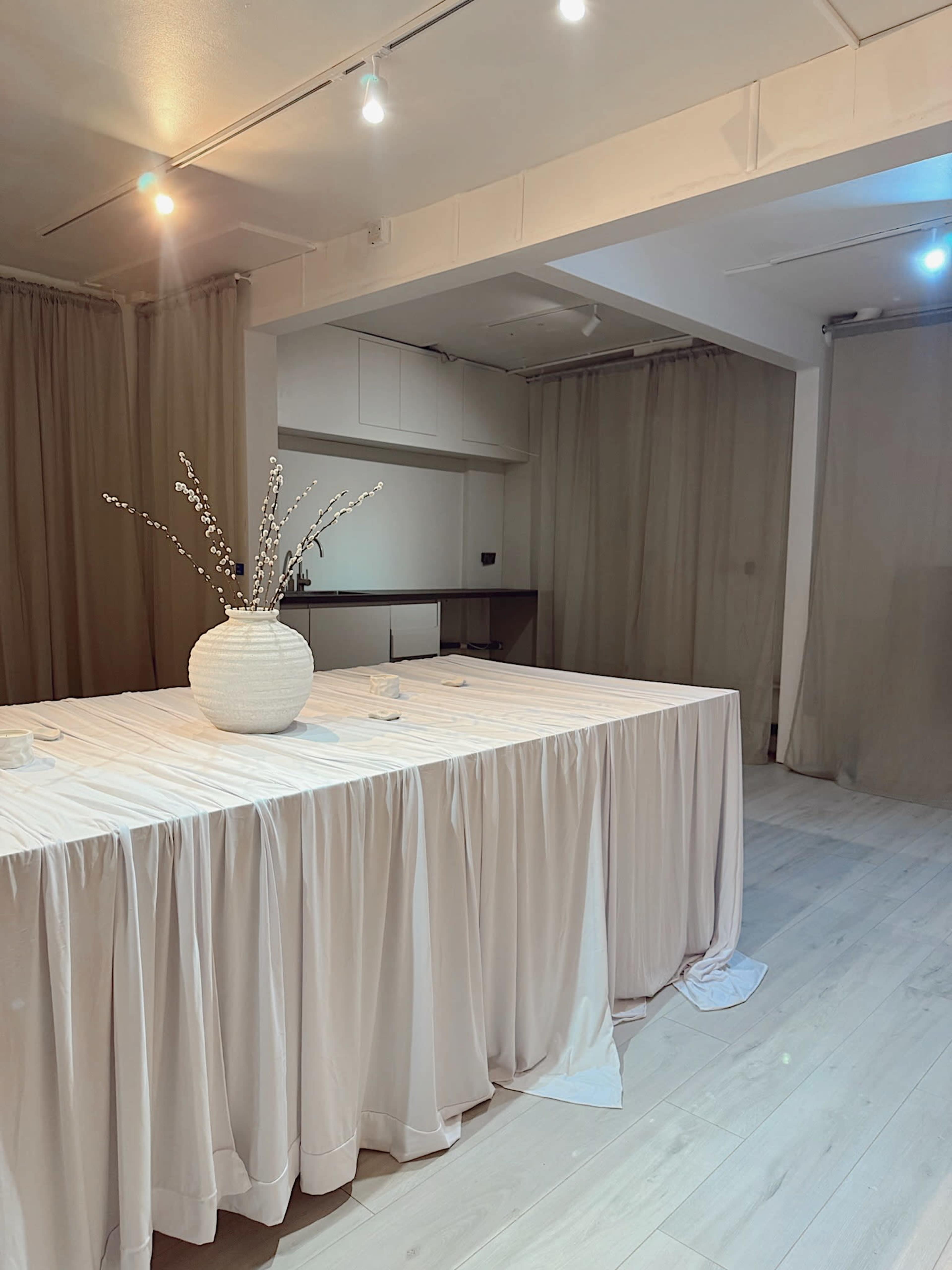 The image features a neatly arranged table covered with a light-colored tablecloth, adorned with a decorative vase and minimalistic decor in a softly lit room.