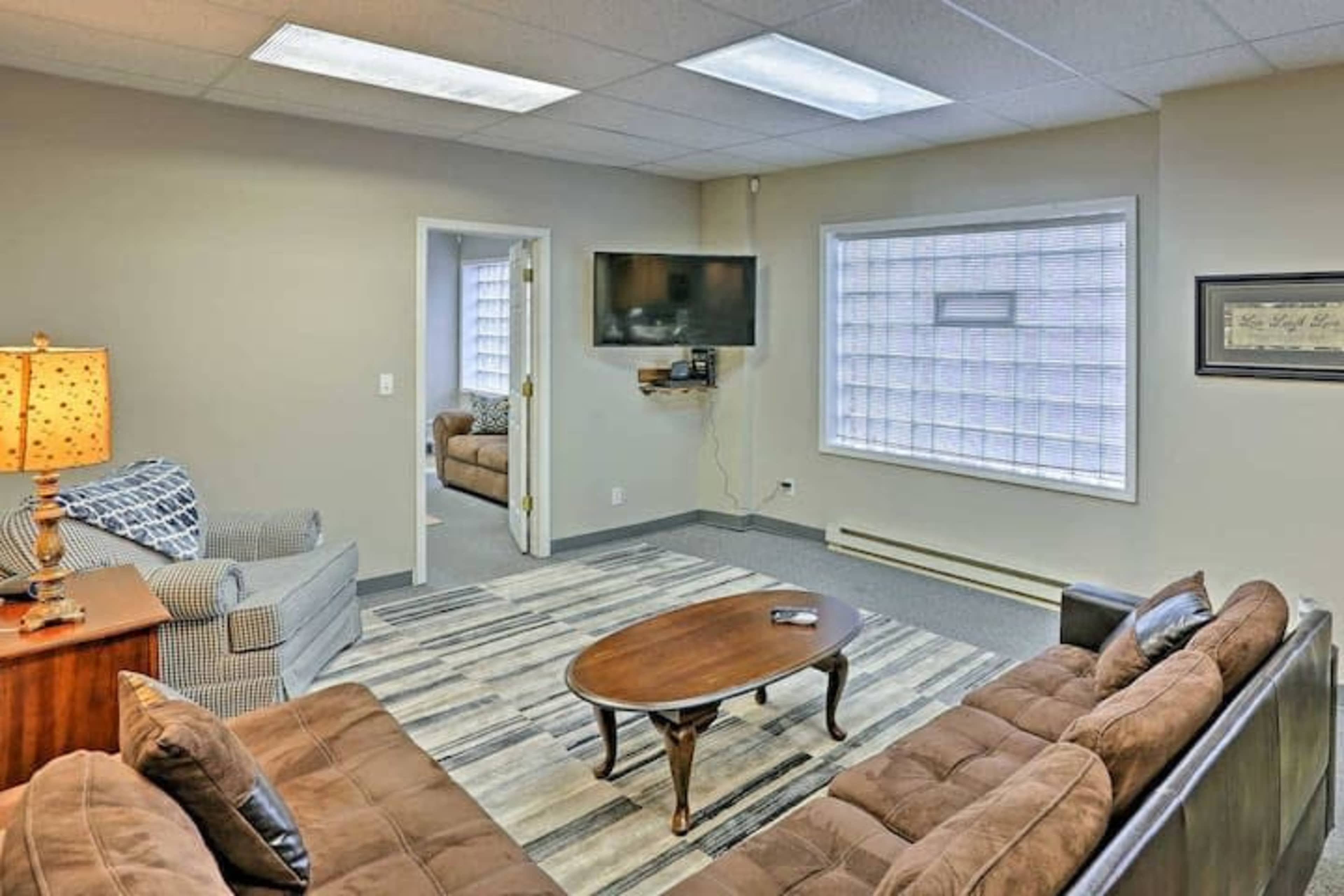 A well-furnished waiting room with two sofas, a coffee table, and a television mounted on the wall.