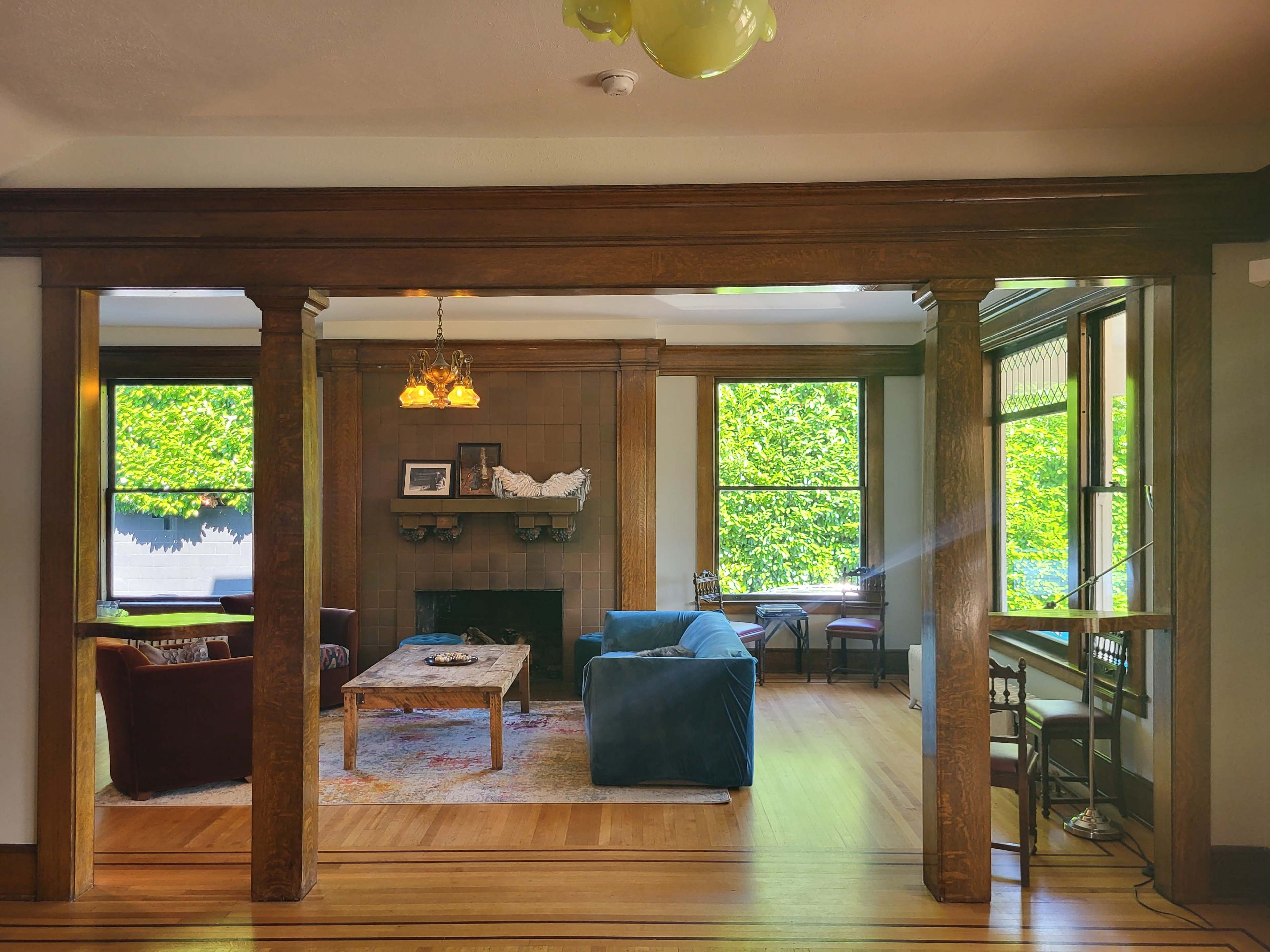 A living room features a fireplace, wooden columns, and large windows that let in natural light.