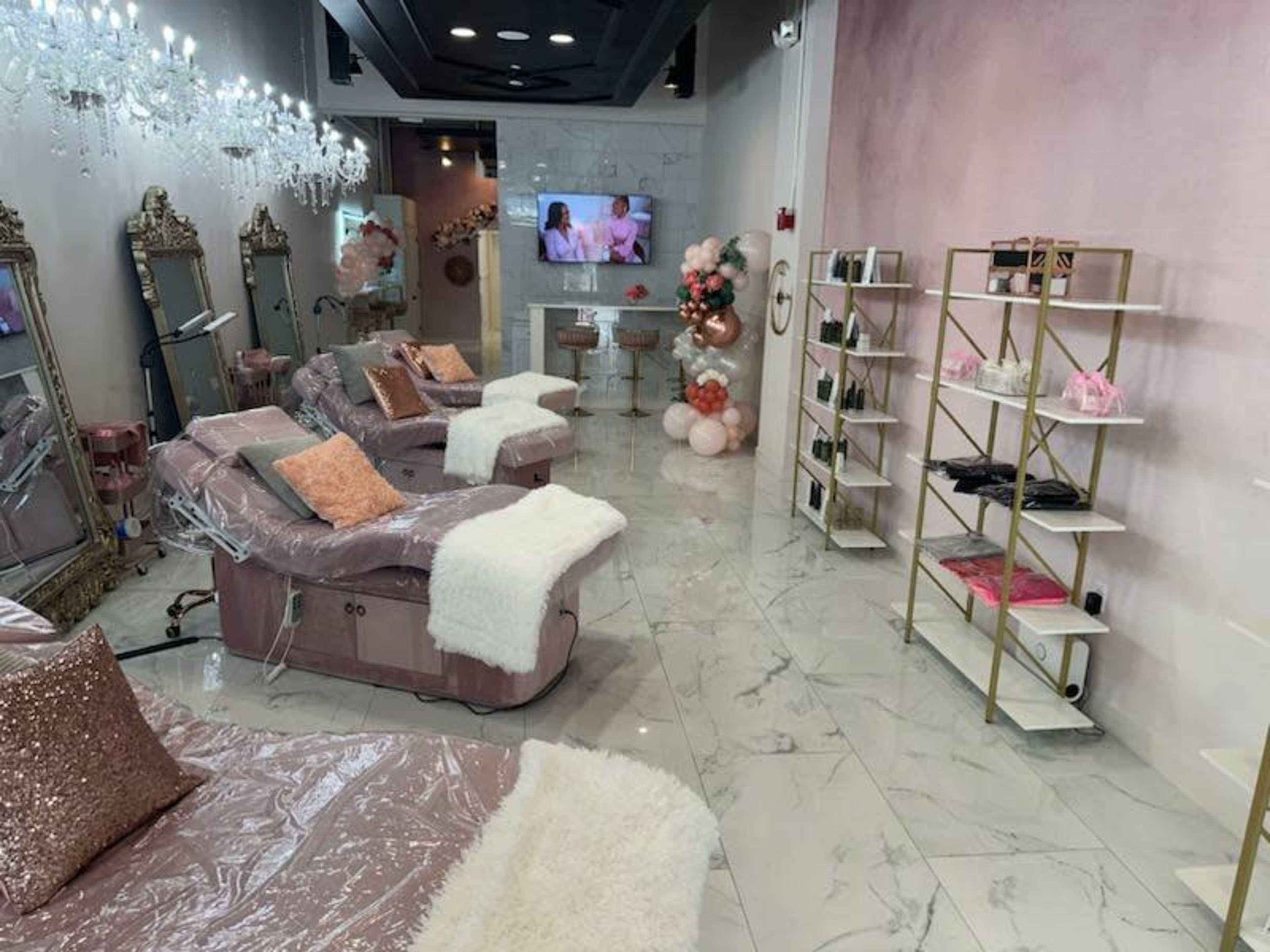 The image shows a beautification salon interior featuring plush seating, elegant mirrors, decorative lighting, and a display shelf with various beauty products.