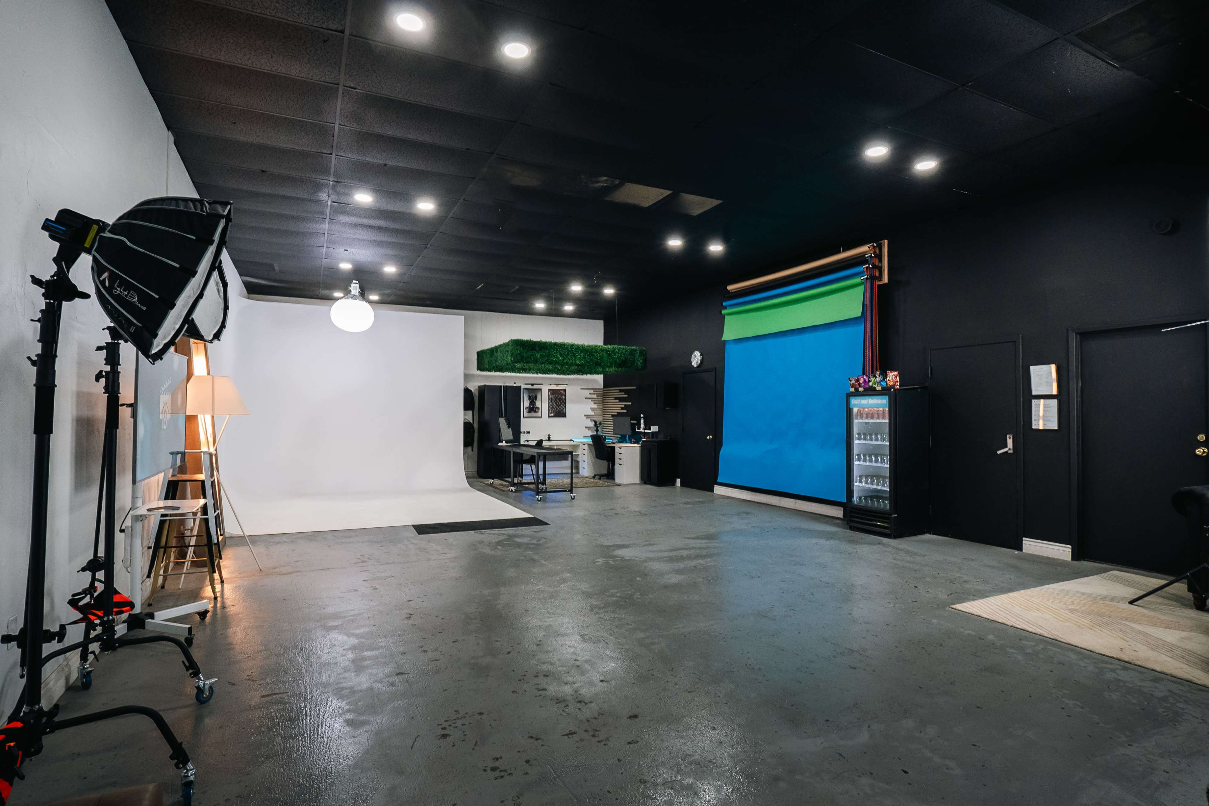 A photography studio with a white backdrop, a blue backdrop, lighting equipment, and a seating area.