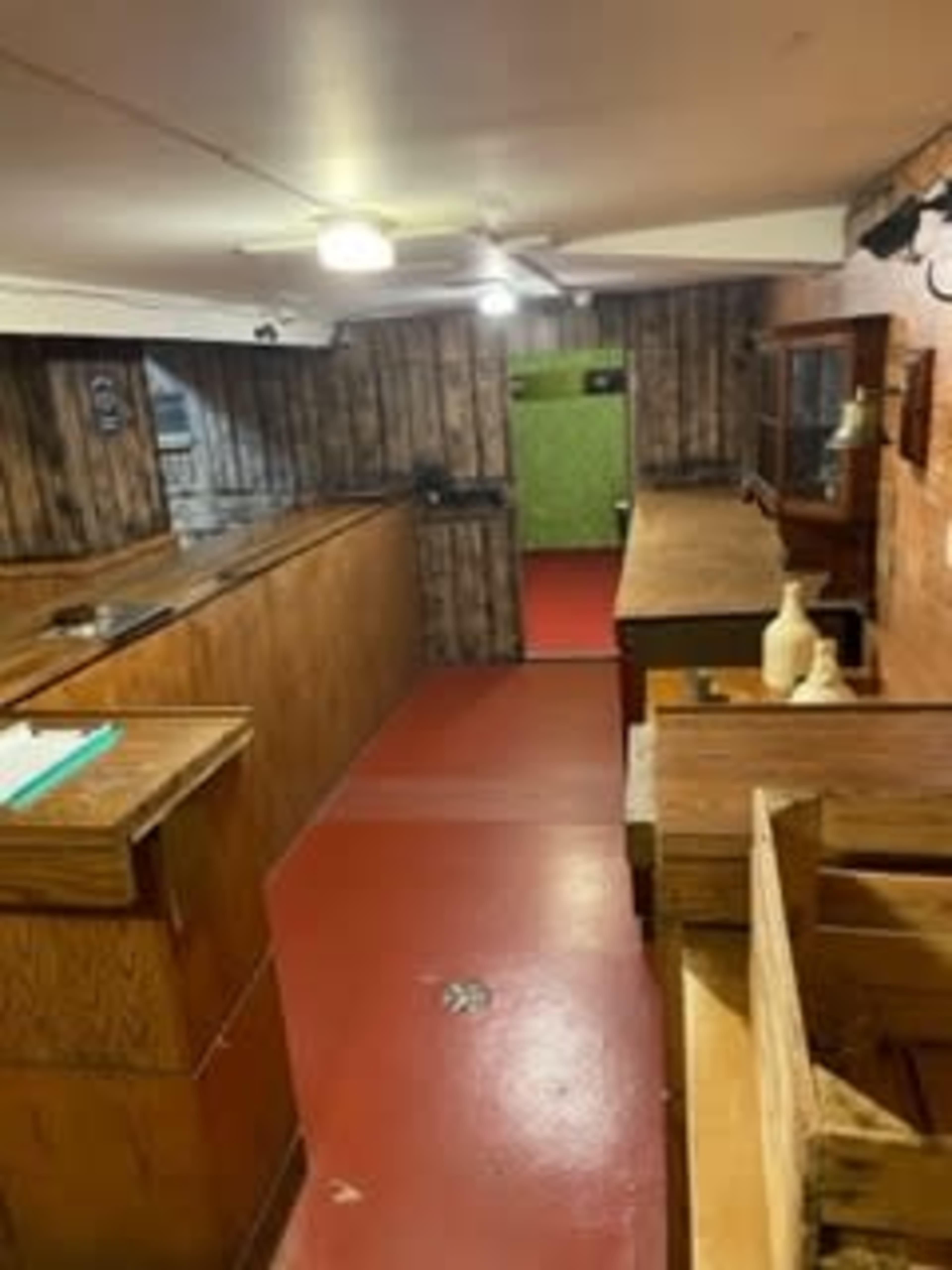 The image shows a basement kitchen with wooden cabinetry, a red floor, and a green wall at the far end.