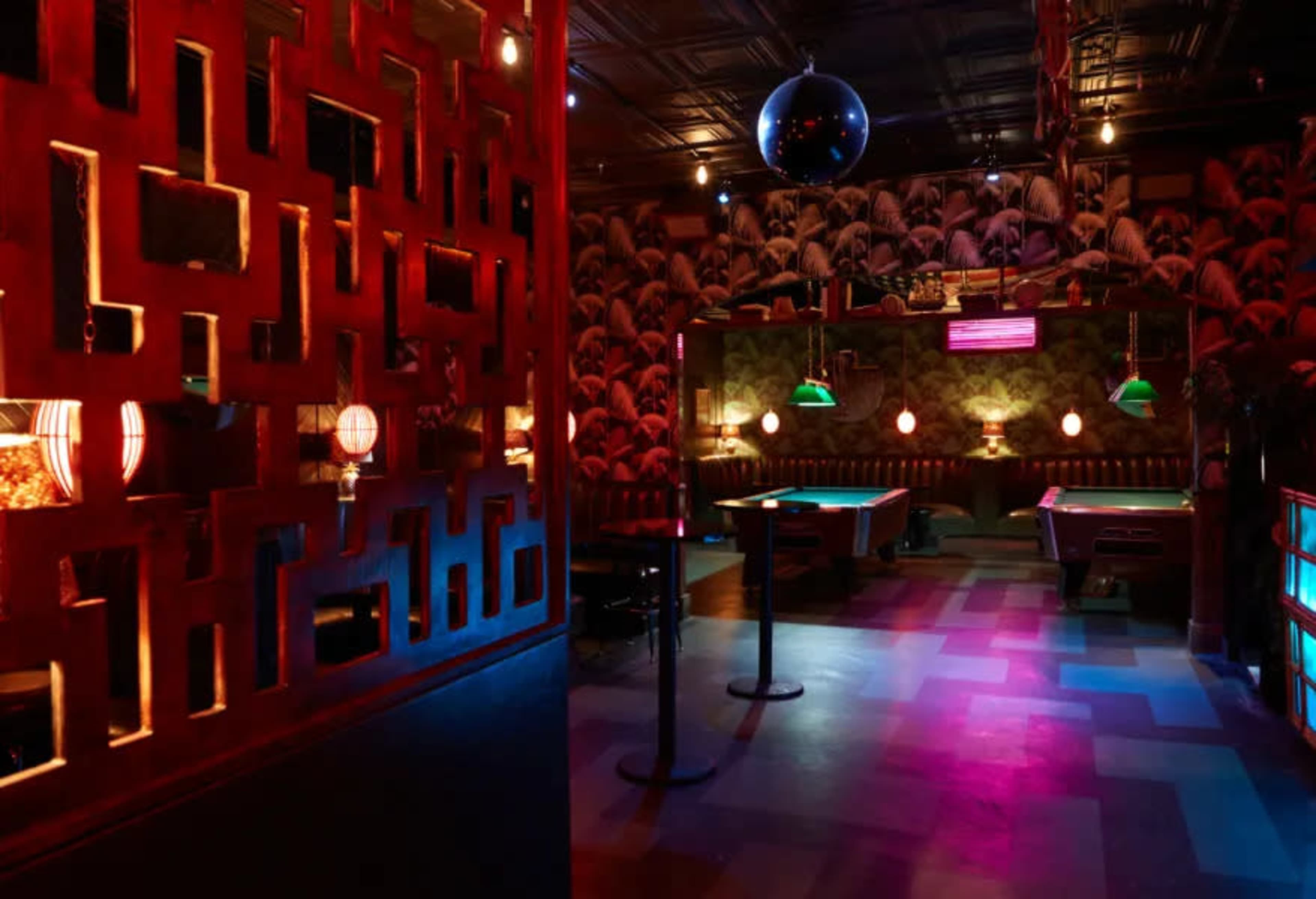 The image features a dimly lit bar interior with colorful lighting, pool tables, and decorative wall elements.