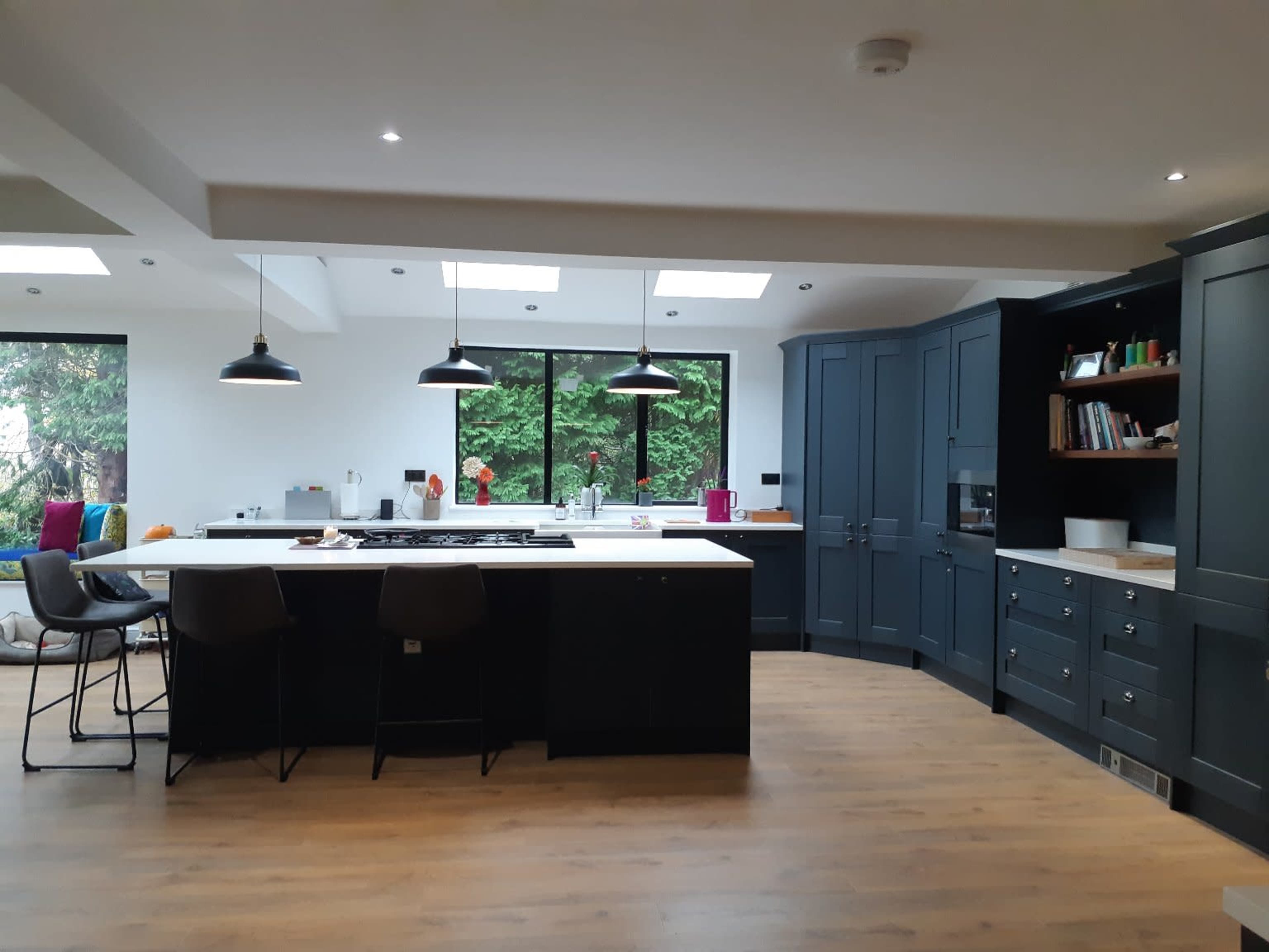 A modern kitchen with dark cabinetry, a large island, and several windows illuminating the space.