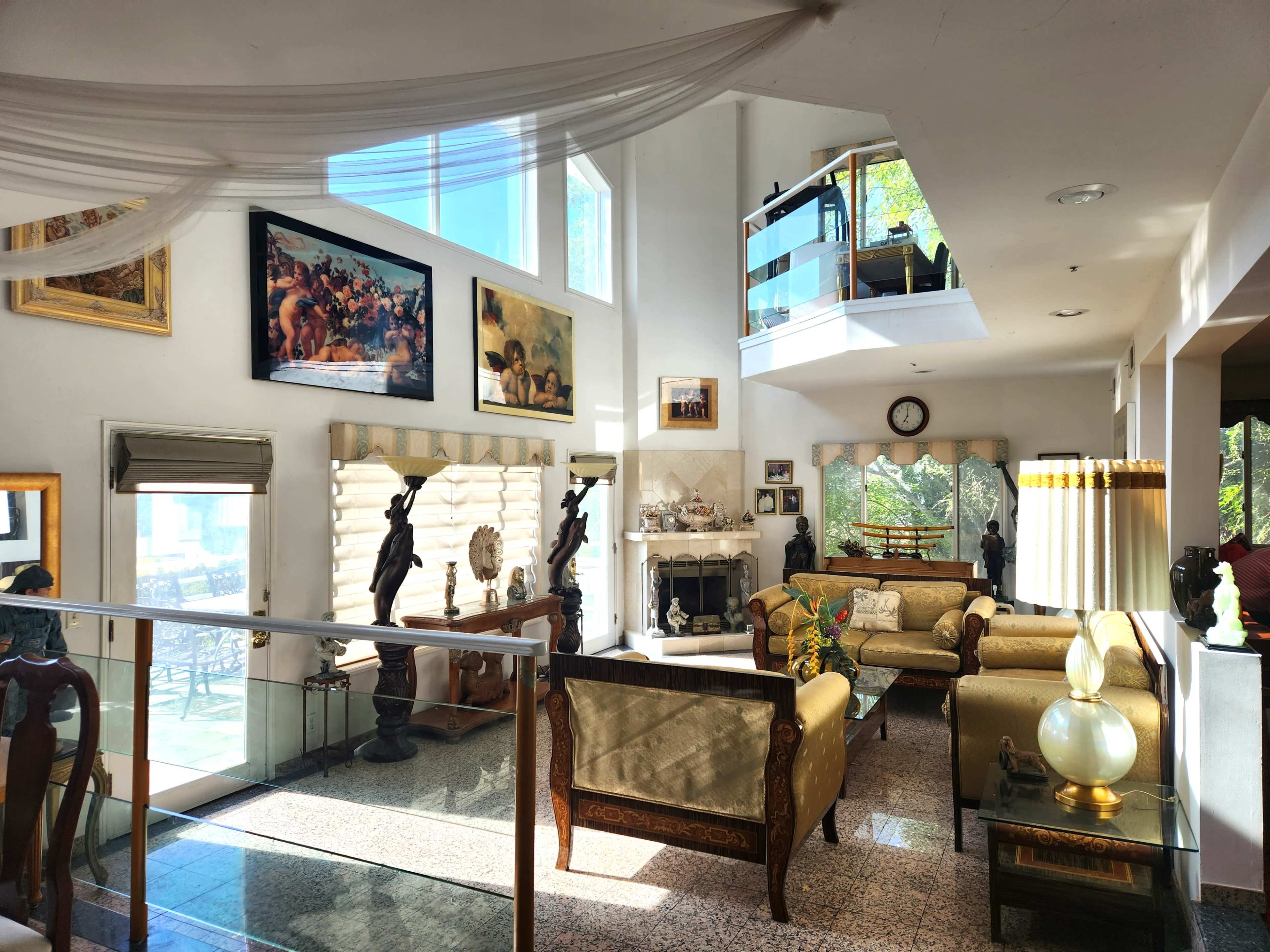 A spacious living room with elegant furniture, large windows, and various artworks adorning the walls.