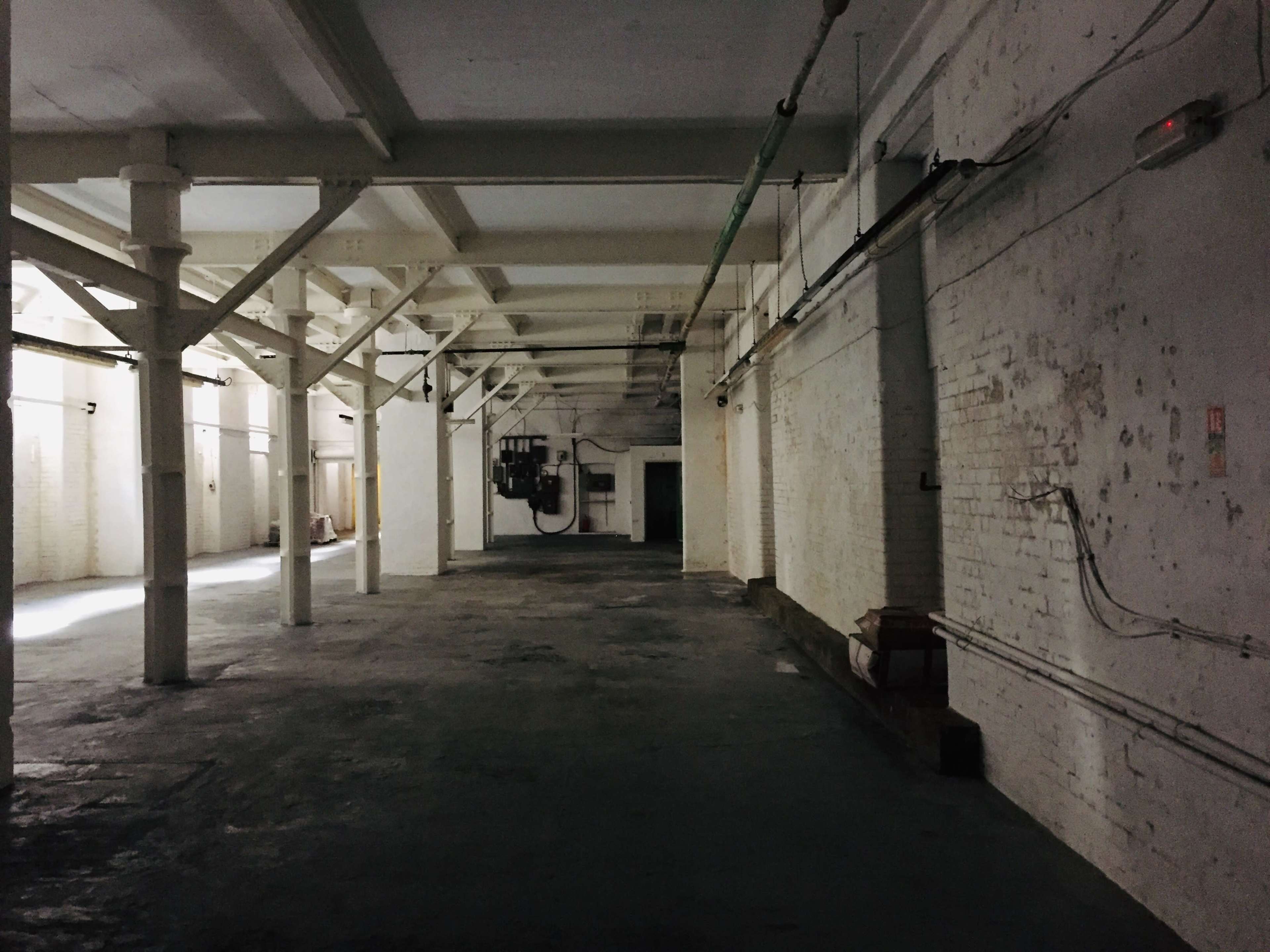 A dark, empty warehouse with exposed beams and bare walls.