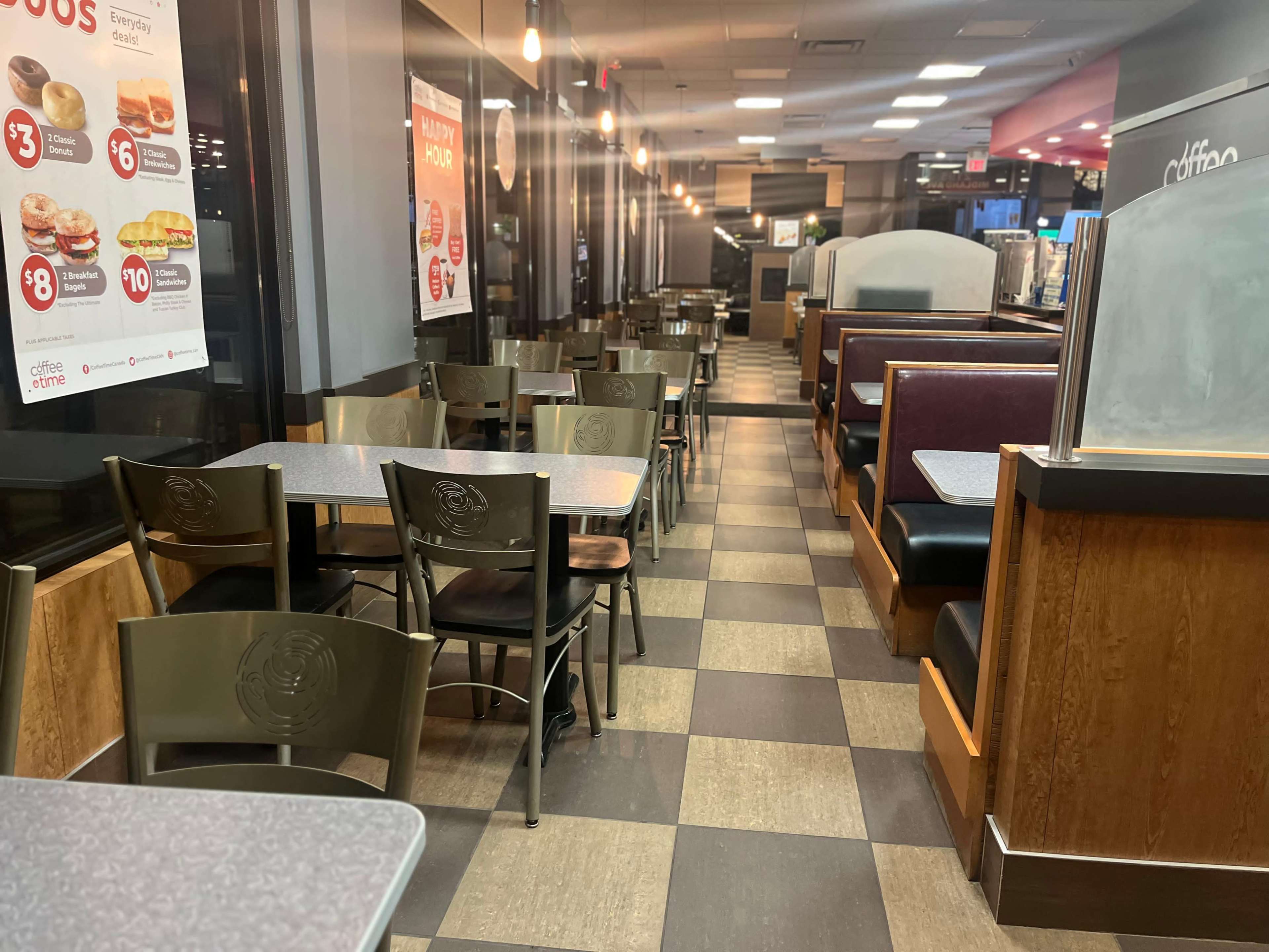 The image shows the interior of a fast-food restaurant with empty tables and chairs arranged in a tiled floor layout.