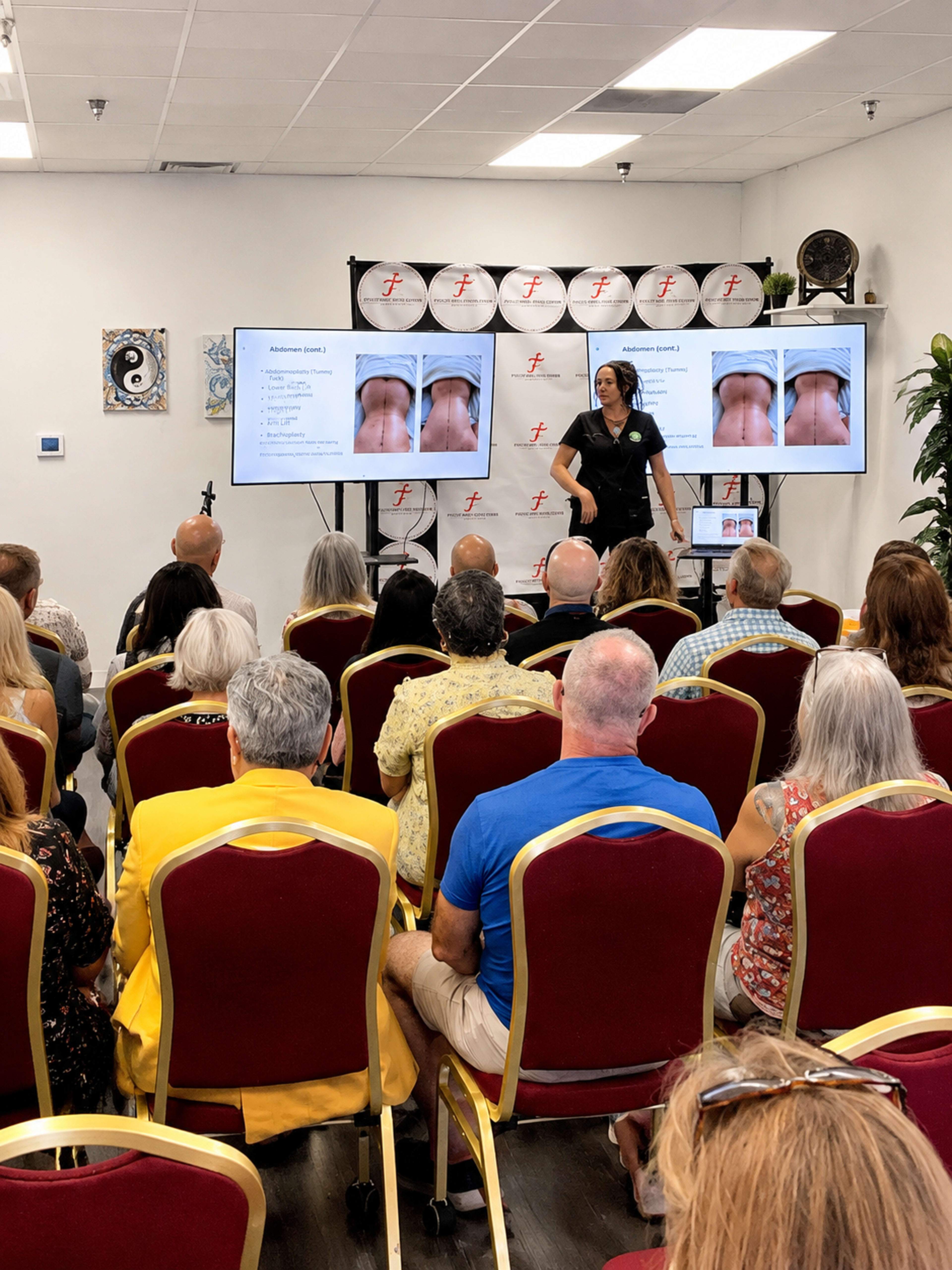A presenter stands in front of a seated audience, showing images on two screens during a seminar on a medical topic.