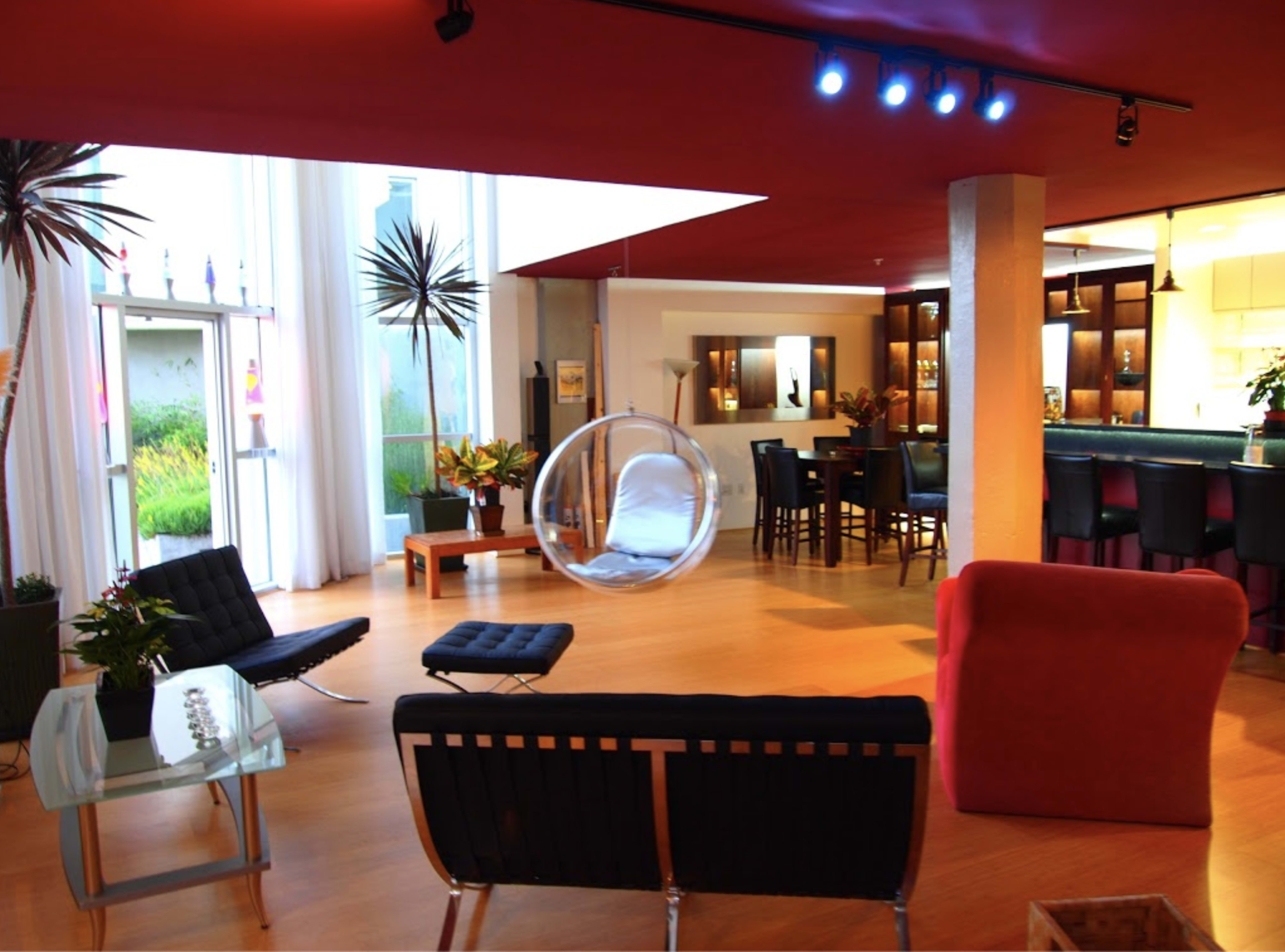A modern living space with a combination of black and red furniture, large windows, and an open kitchen area.