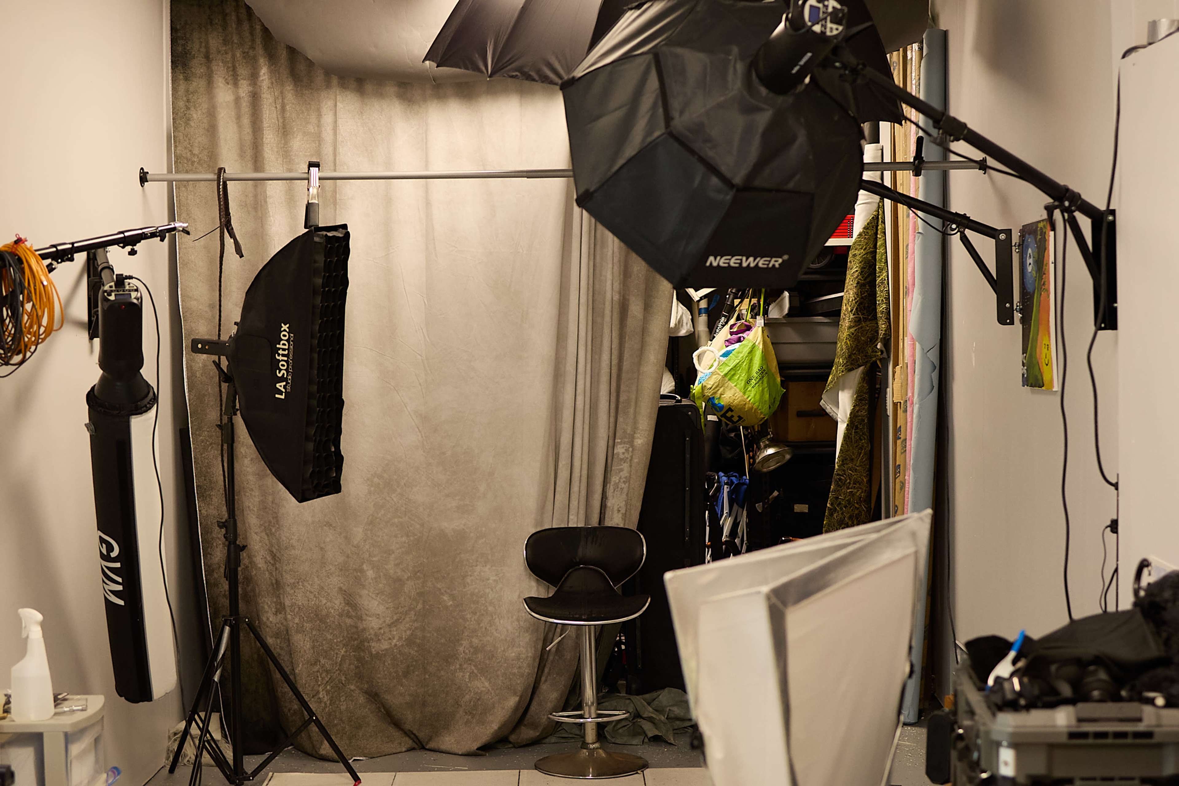 The image shows a photography studio with various lighting equipment and a backdrop set up in a narrow space.