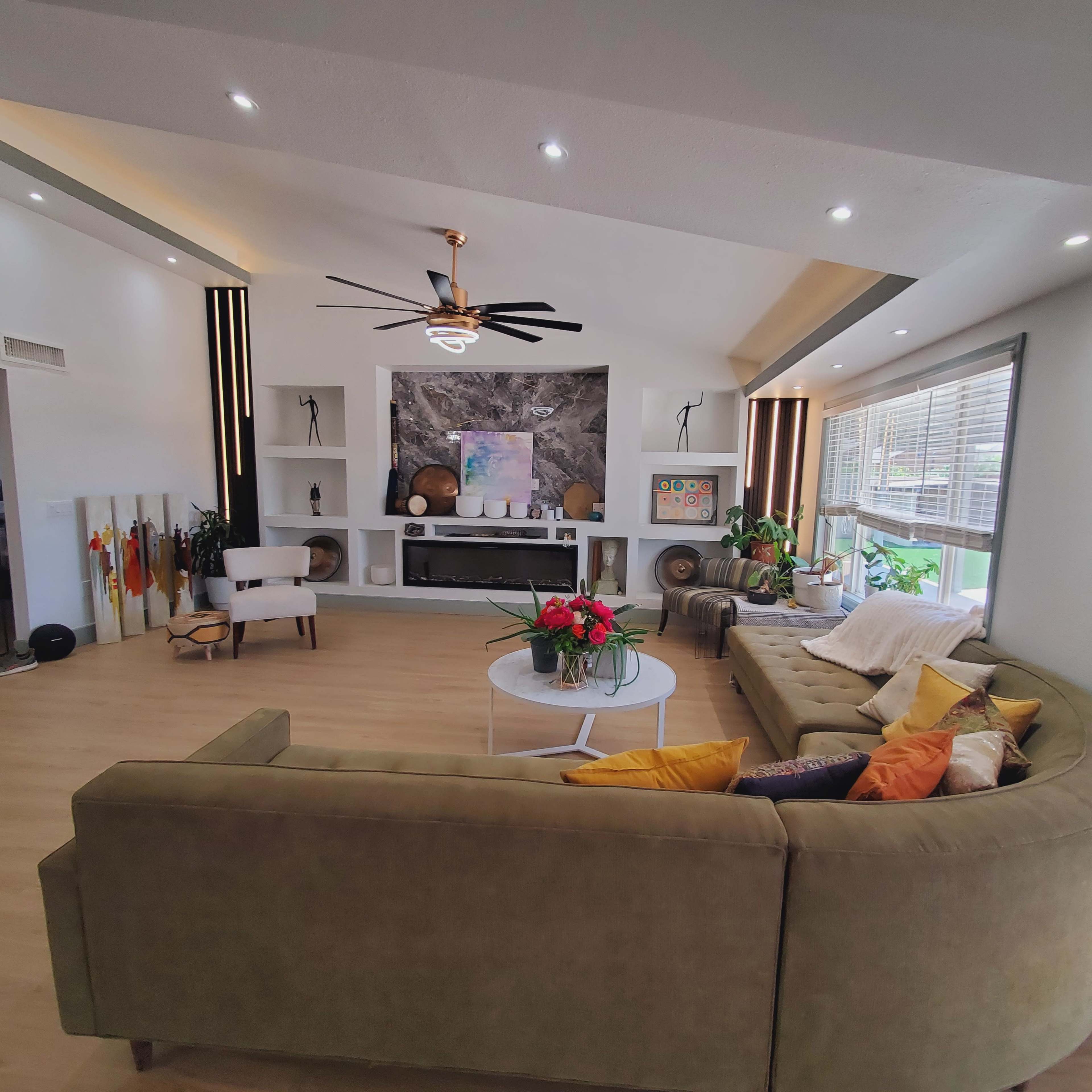 The image shows a modern living room featuring a large sectional sofa, a coffee table, and a decorative fireplace surrounded by built-in shelves.