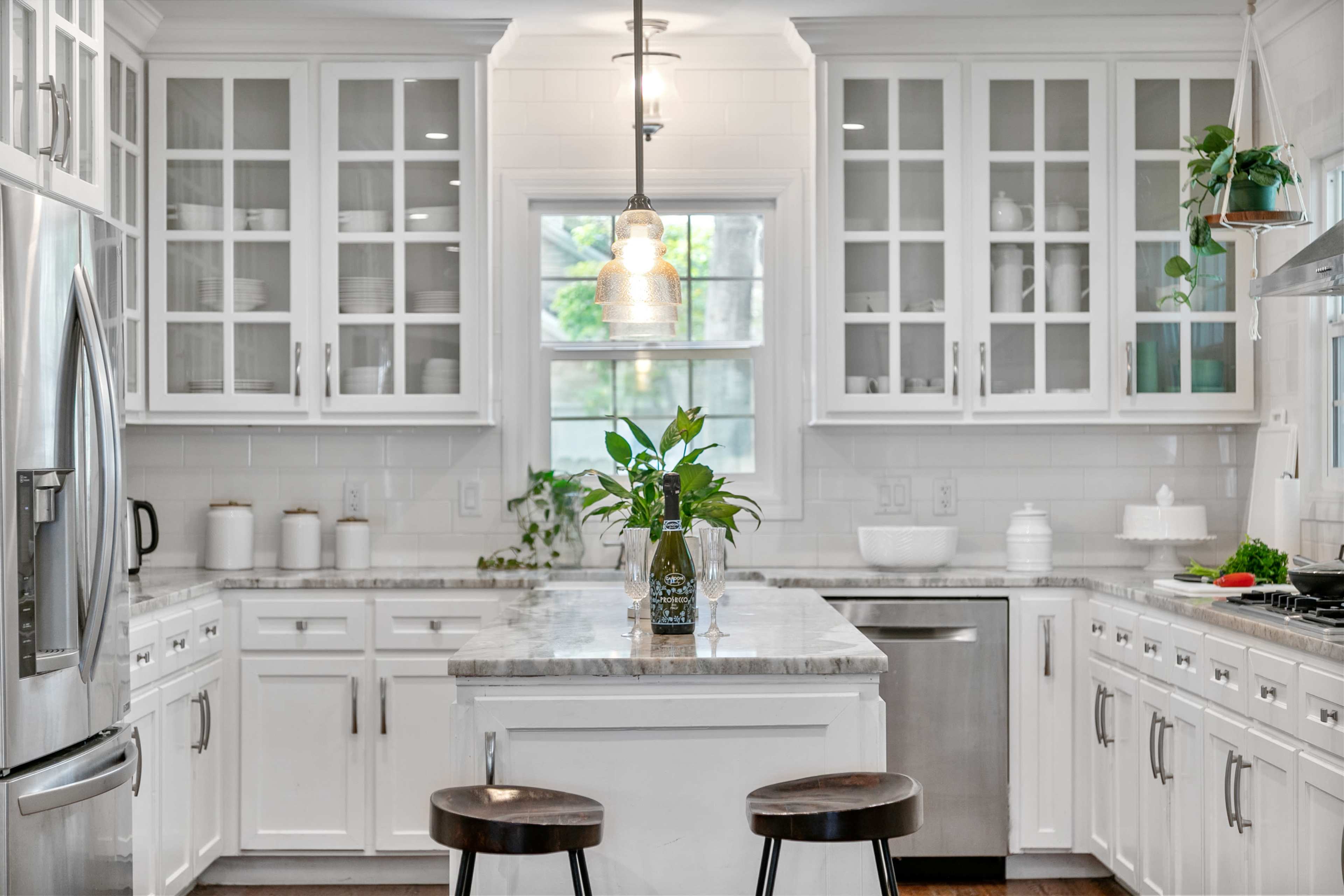 A modern kitchen with white cabinetry, a central island, and stainless steel appliances.