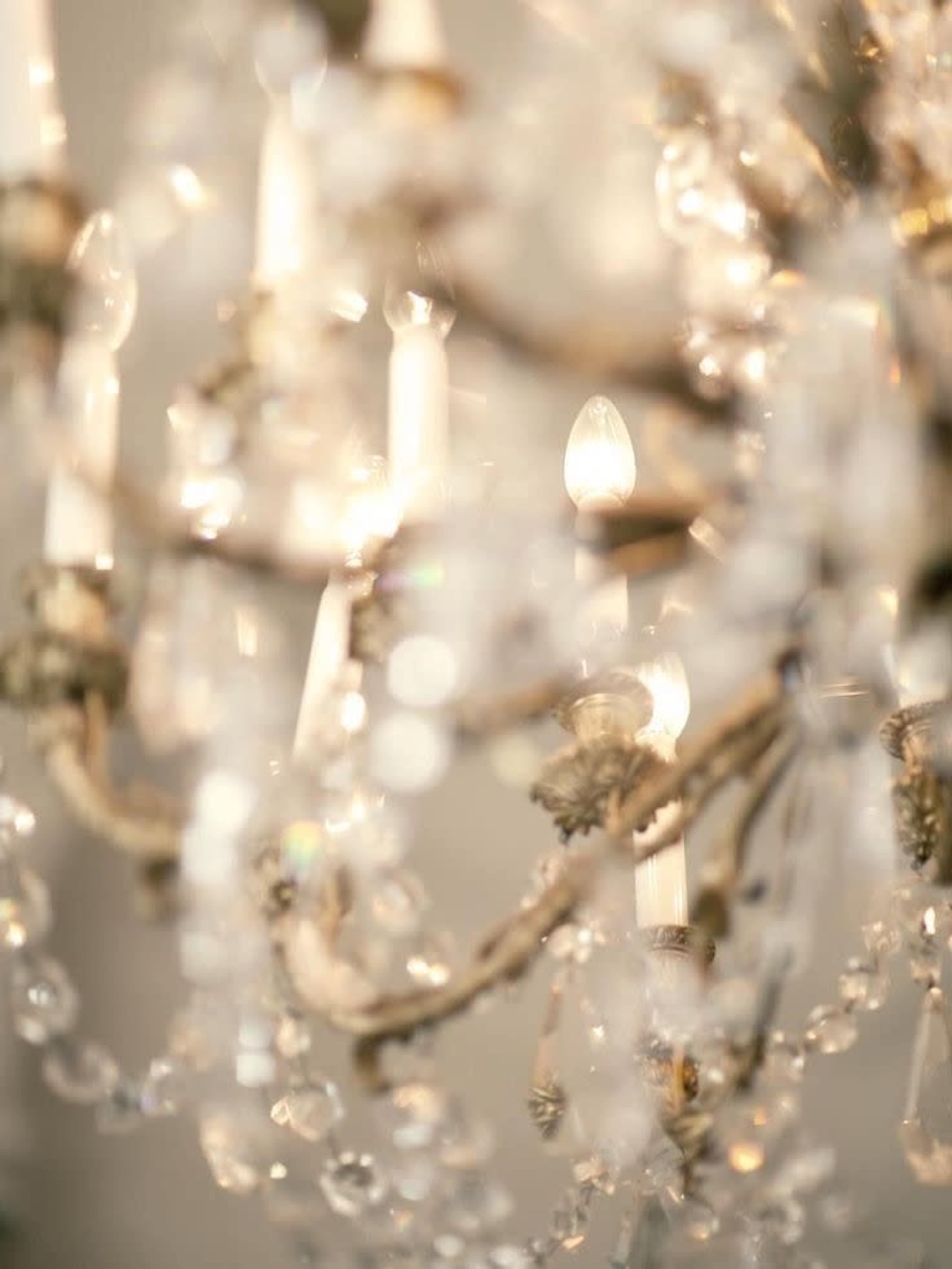 A close-up of a chandelier featuring crystal accents and illuminated candle-like bulbs.