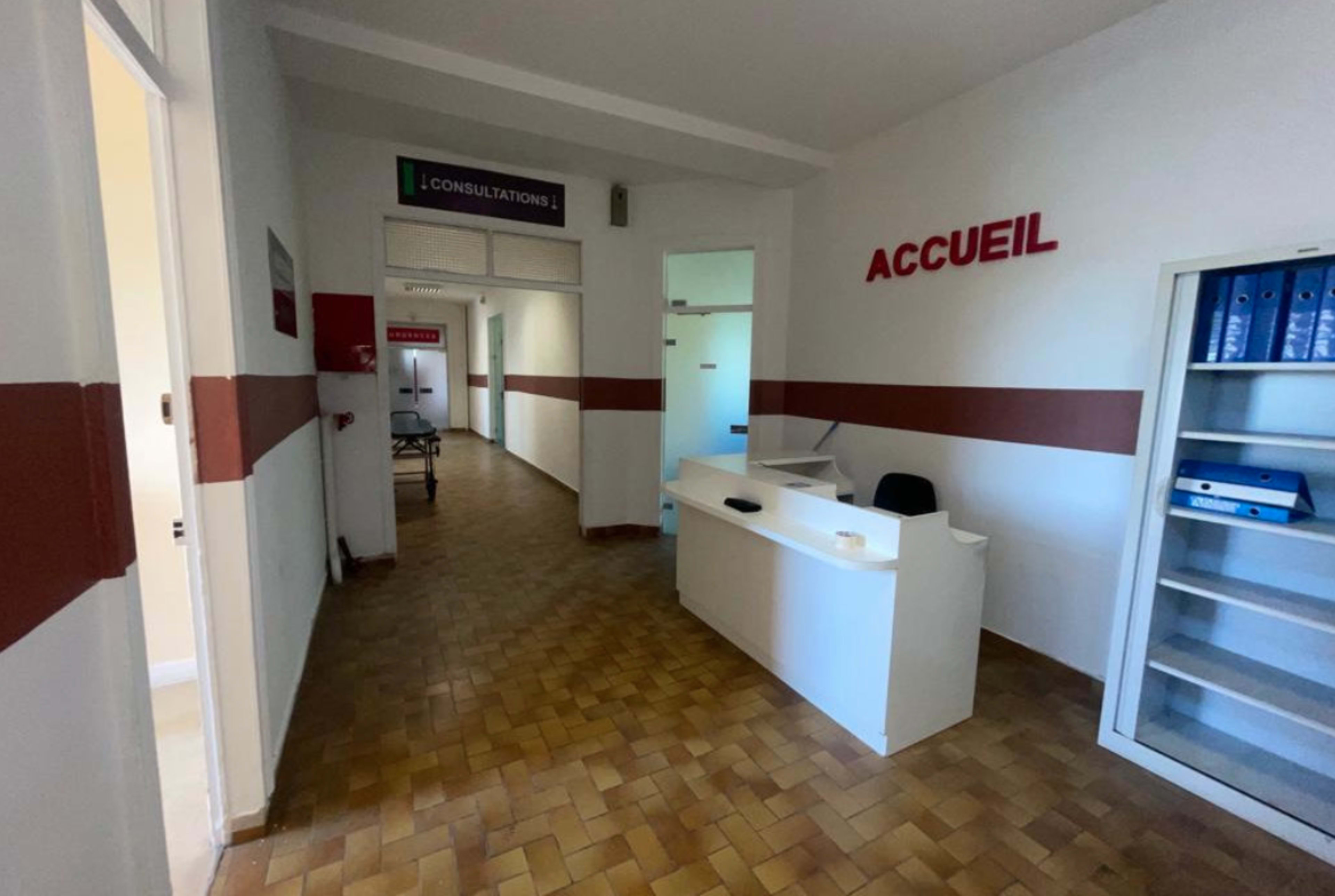 A reception area in a medical facility with a front desk and a hallway leading to consultation rooms.