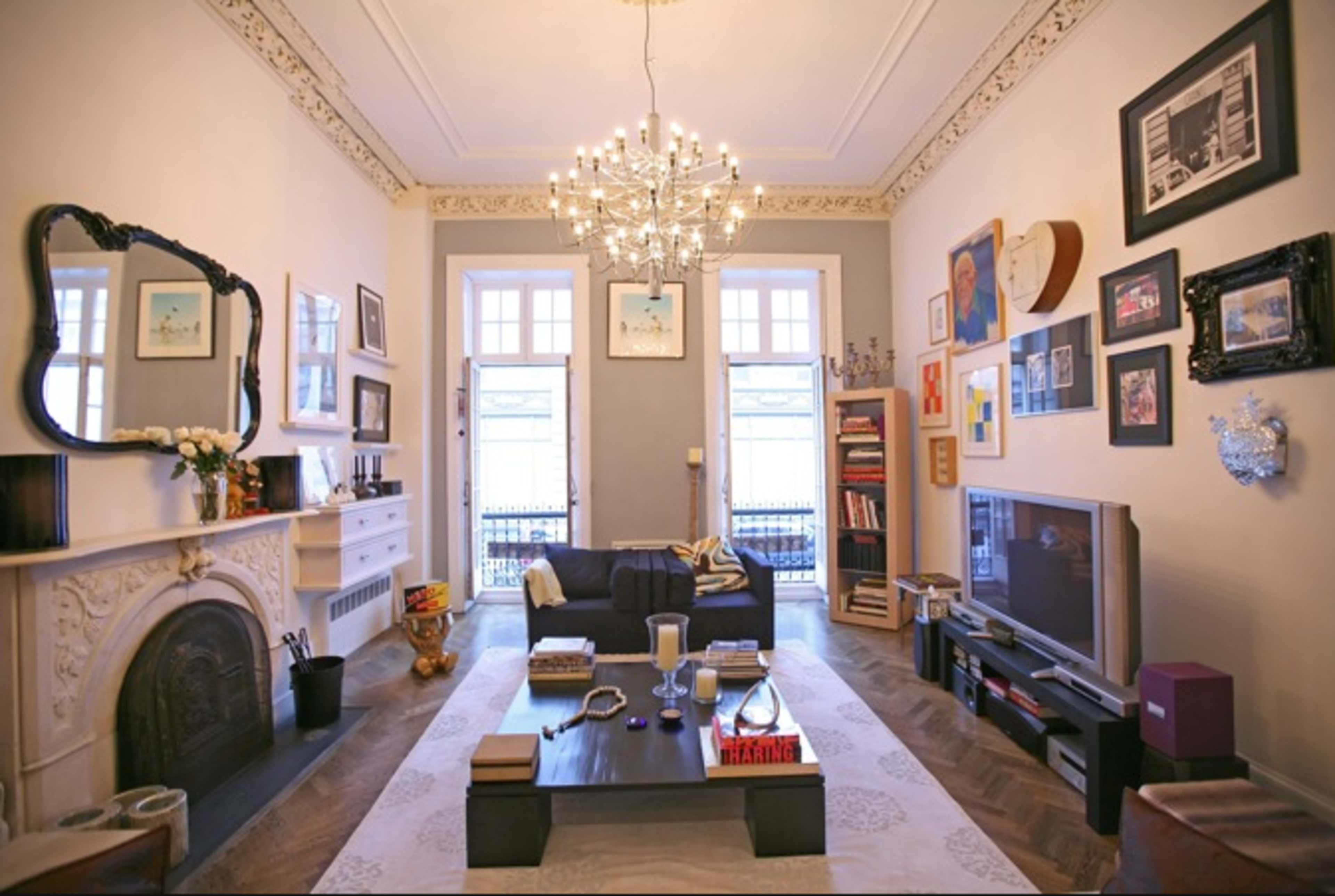 The living room features a chandelier, a dark sofa, a low coffee table, and an array of framed pictures on the walls.
