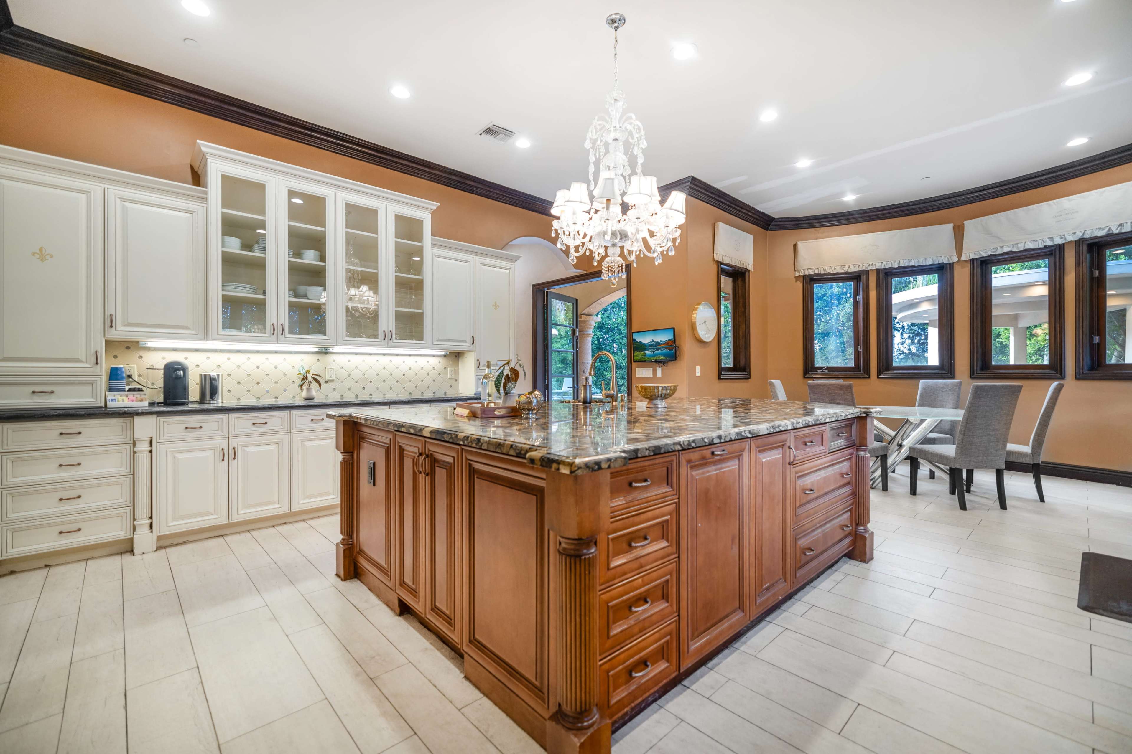 A spacious kitchen featuring a large wooden island with a granite countertop, surrounded by light-colored cabinetry and modern appliances.
