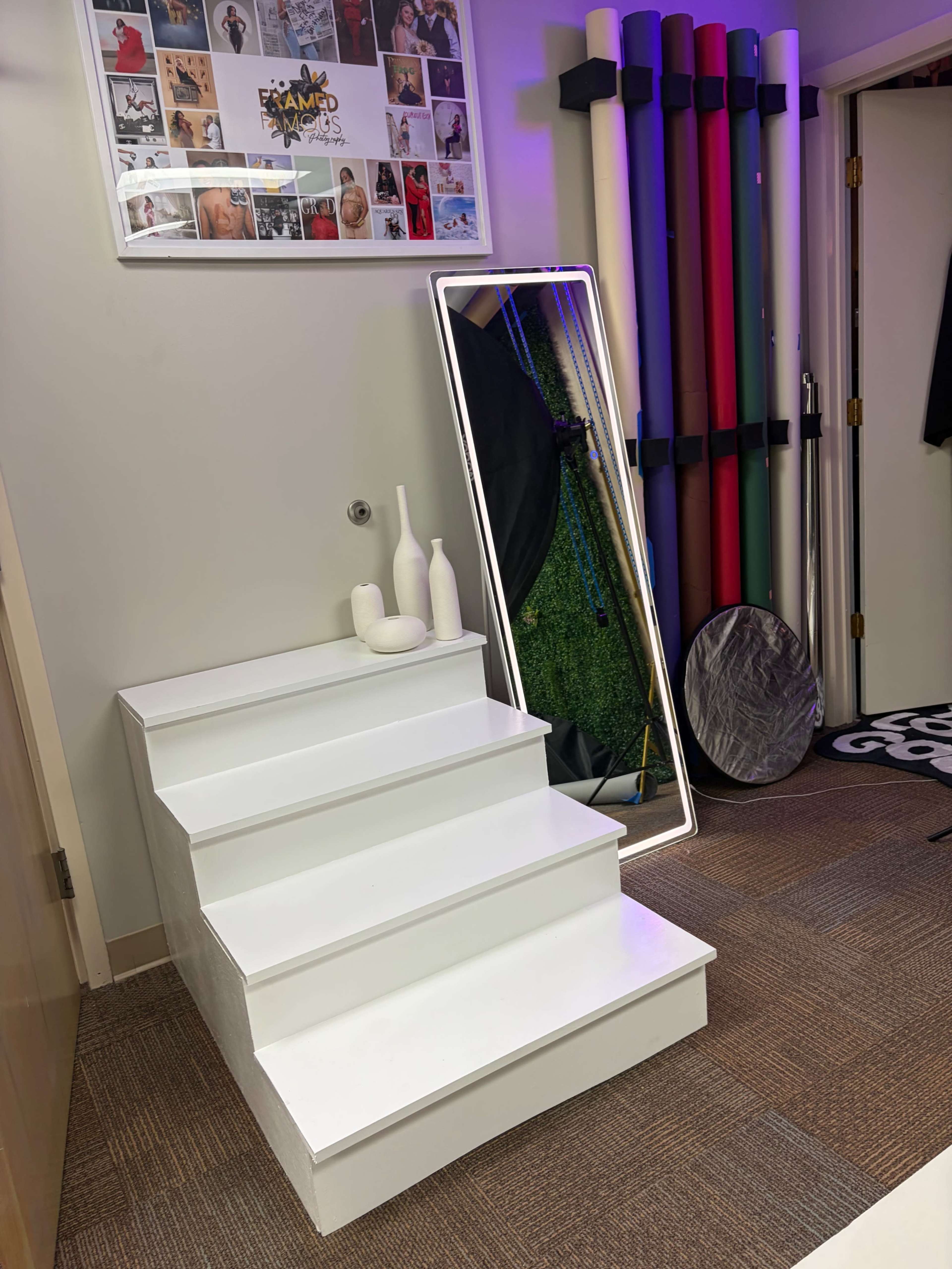 The image shows a set of white stairs leading to a room with a large mirror, decorative vases, and various colorful exercise equipment hanging on the wall.