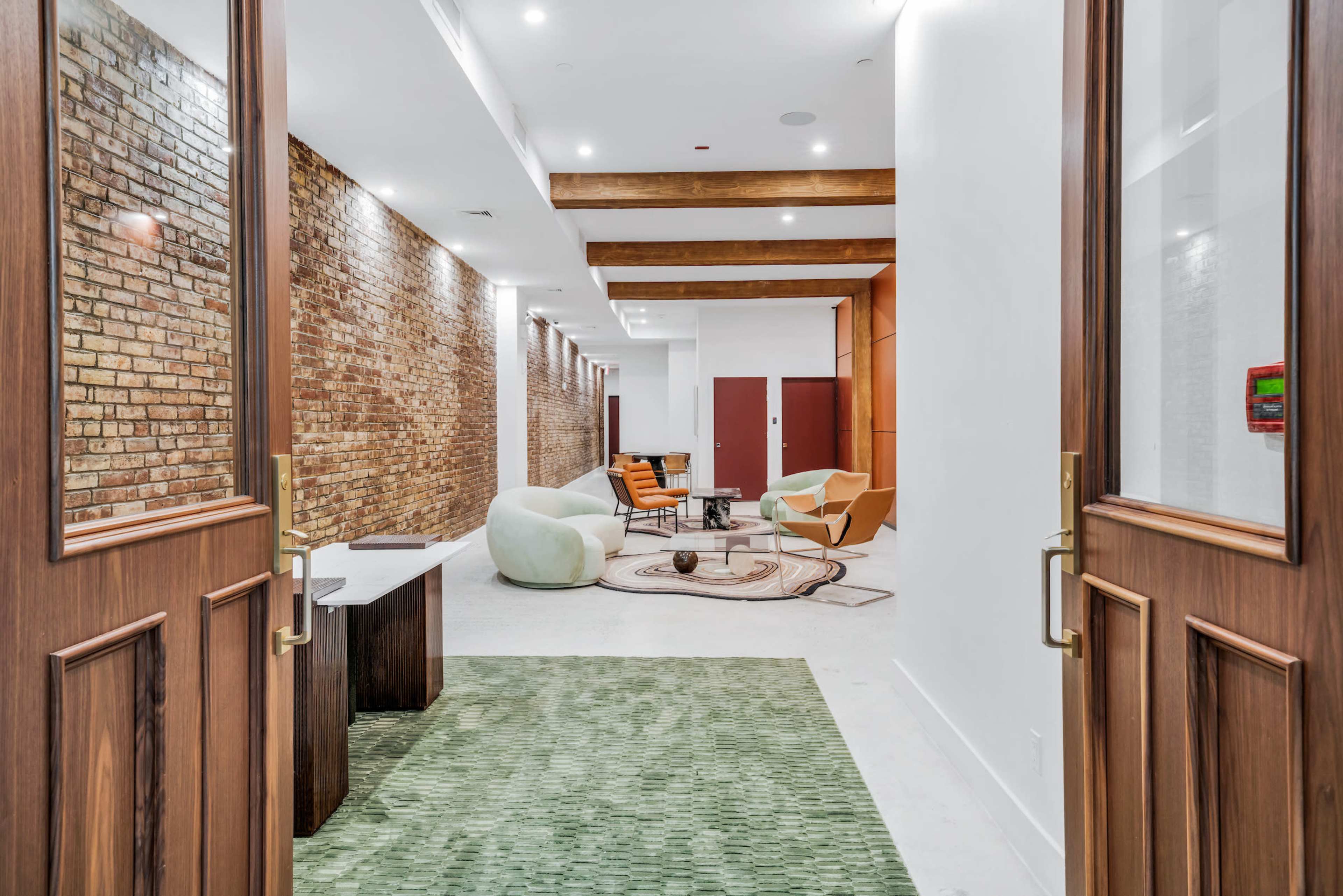 A spacious room features a mix of textured brick and smooth white walls, furnished with modern seating and a large area rug.
