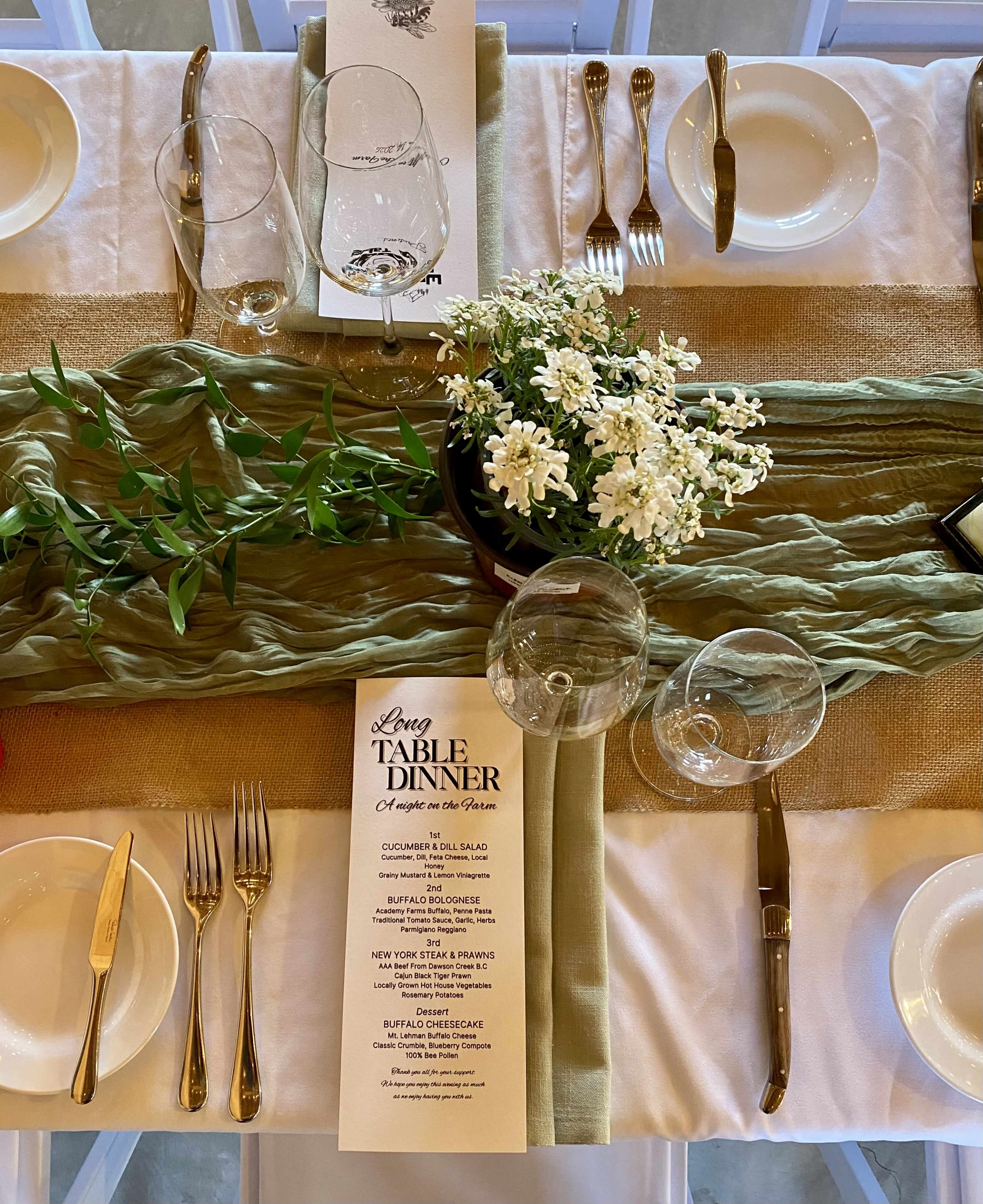 A elegantly set dining table features a floral centerpiece, a menu, glassware, and coordinated table linens.