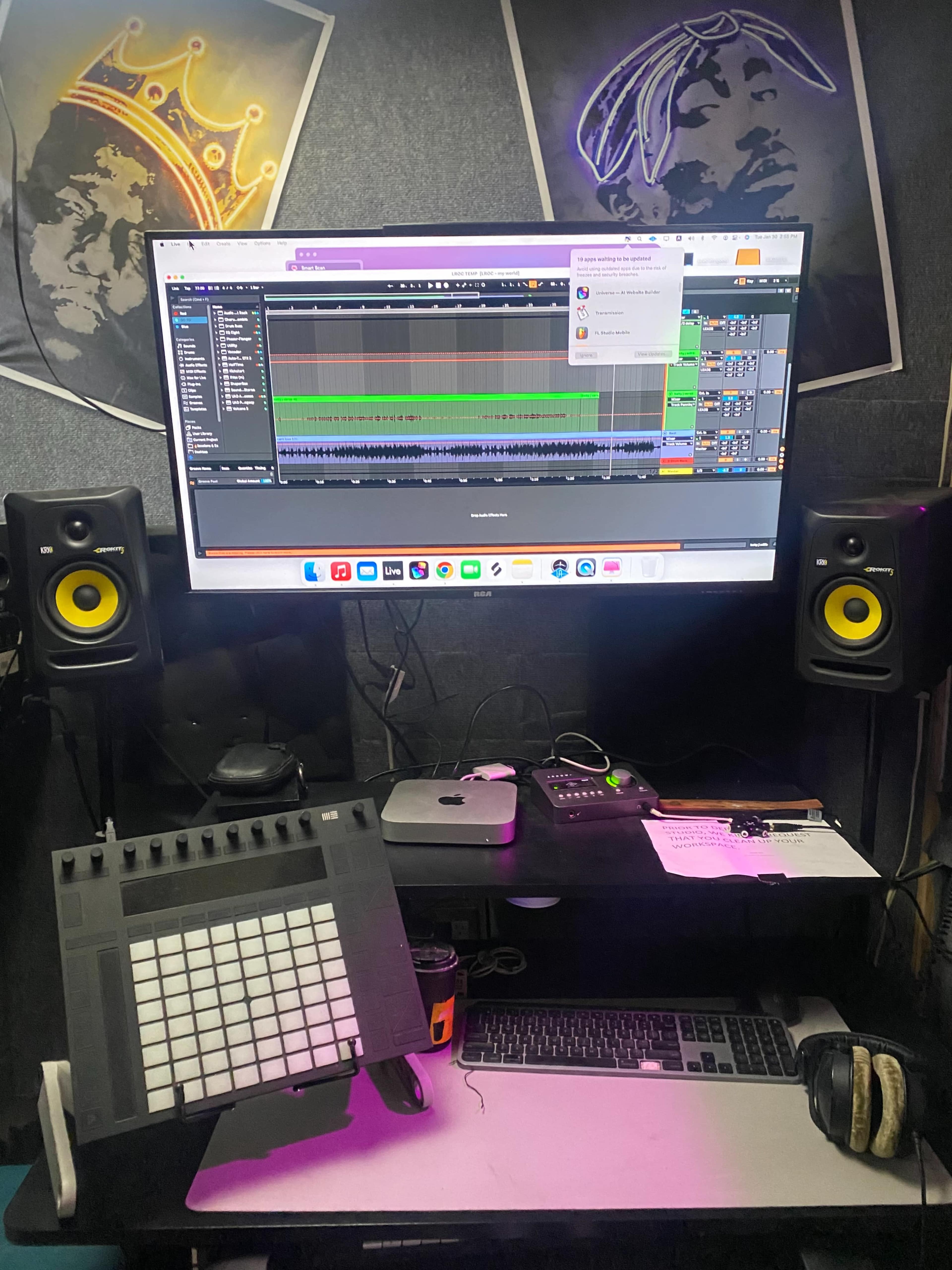 A digital audio workstation setup features a large monitor displaying music software, MIDI controller, and studio monitors on a desk.