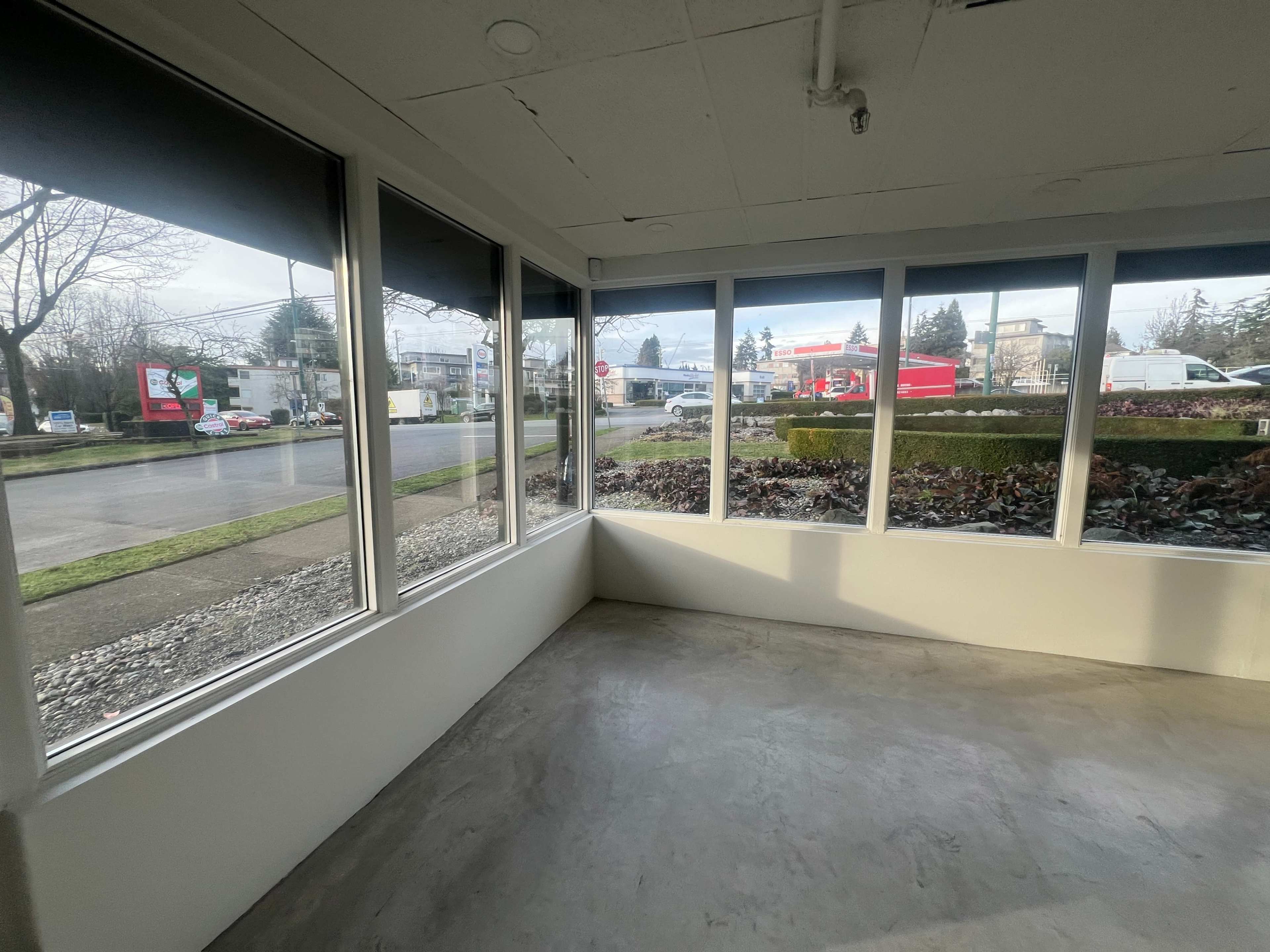 The image shows a corner of a room with large windows overlooking a street and parked vehicles outside.