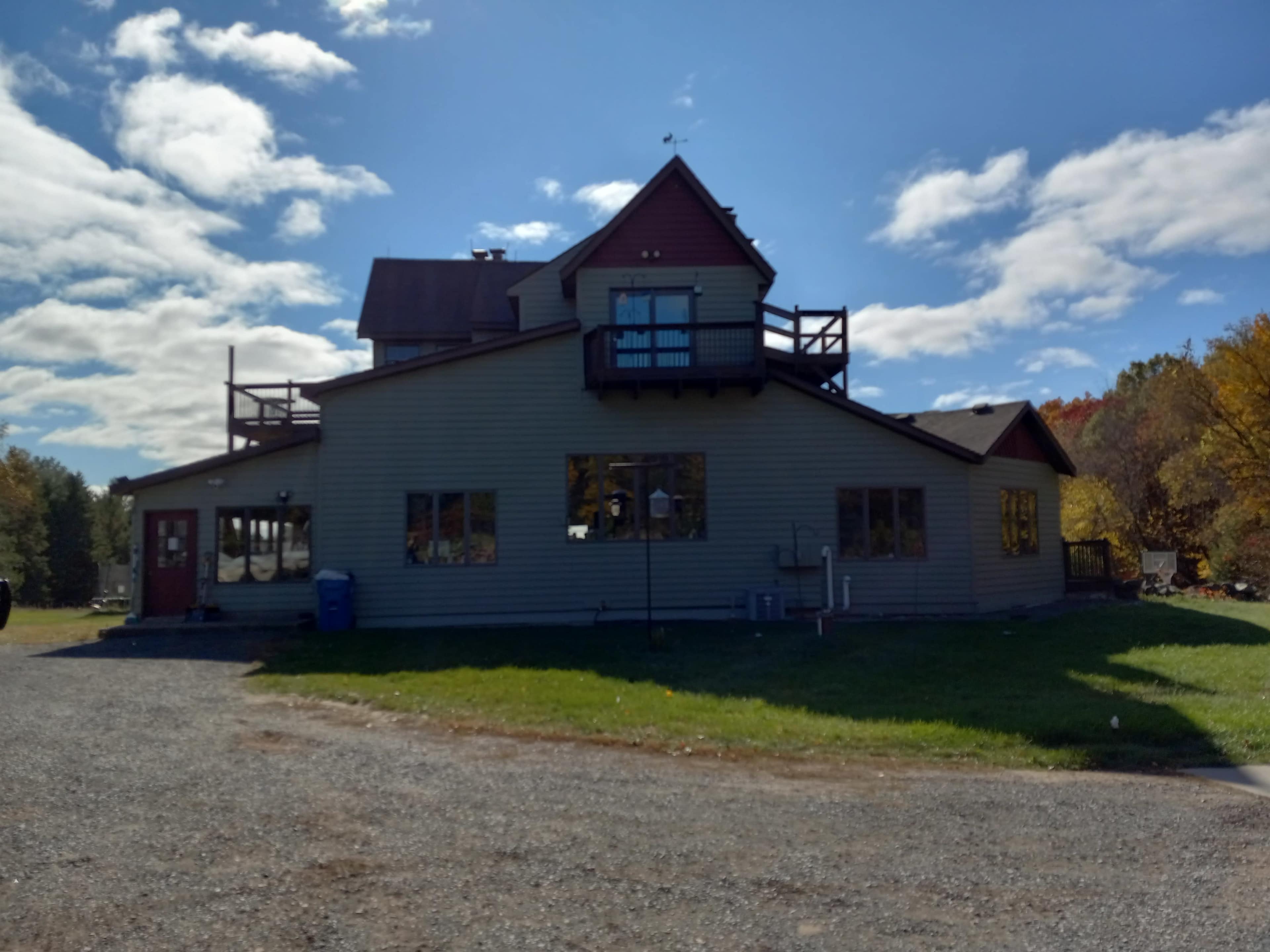 A large, two-story house with multiple windows and a steeply pitched roof is situated on a grassy plot.
