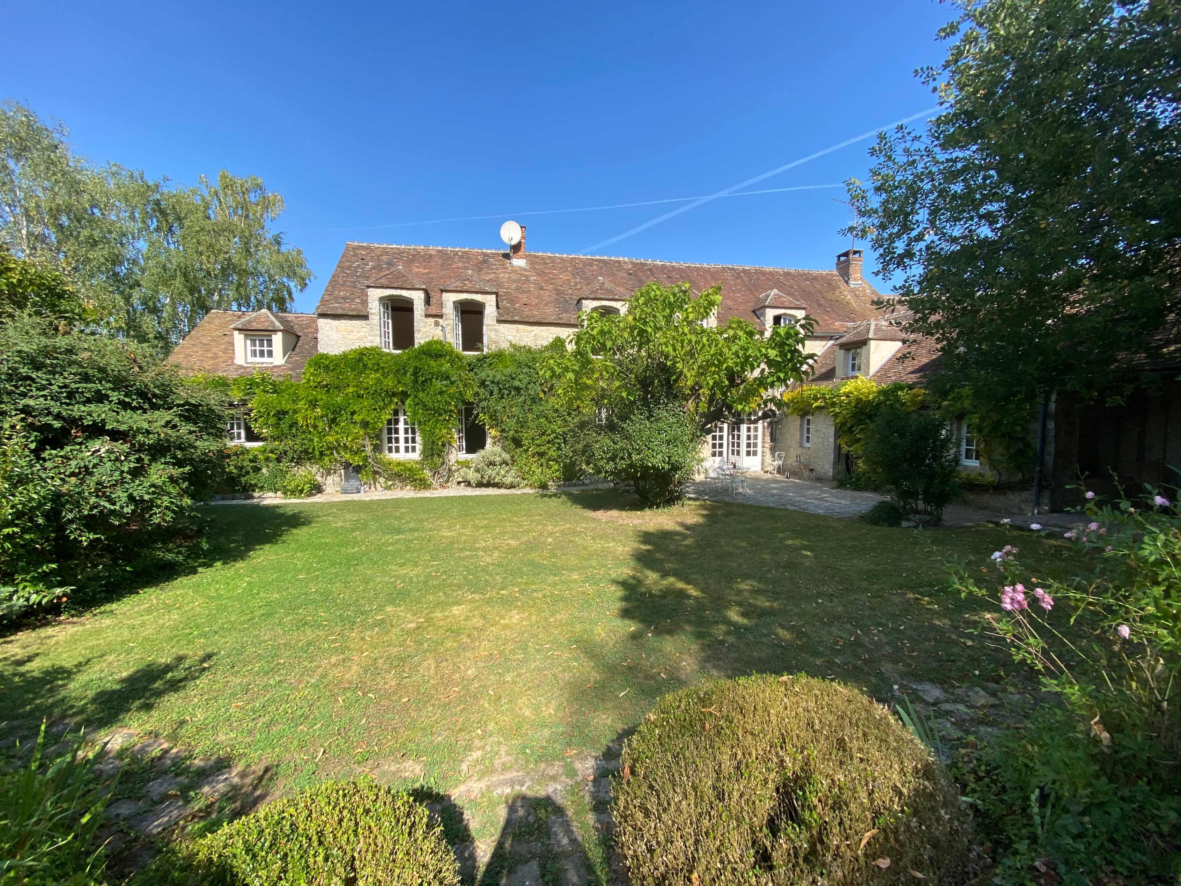 A large stone house surrounded by greenery and a well-maintained garden.