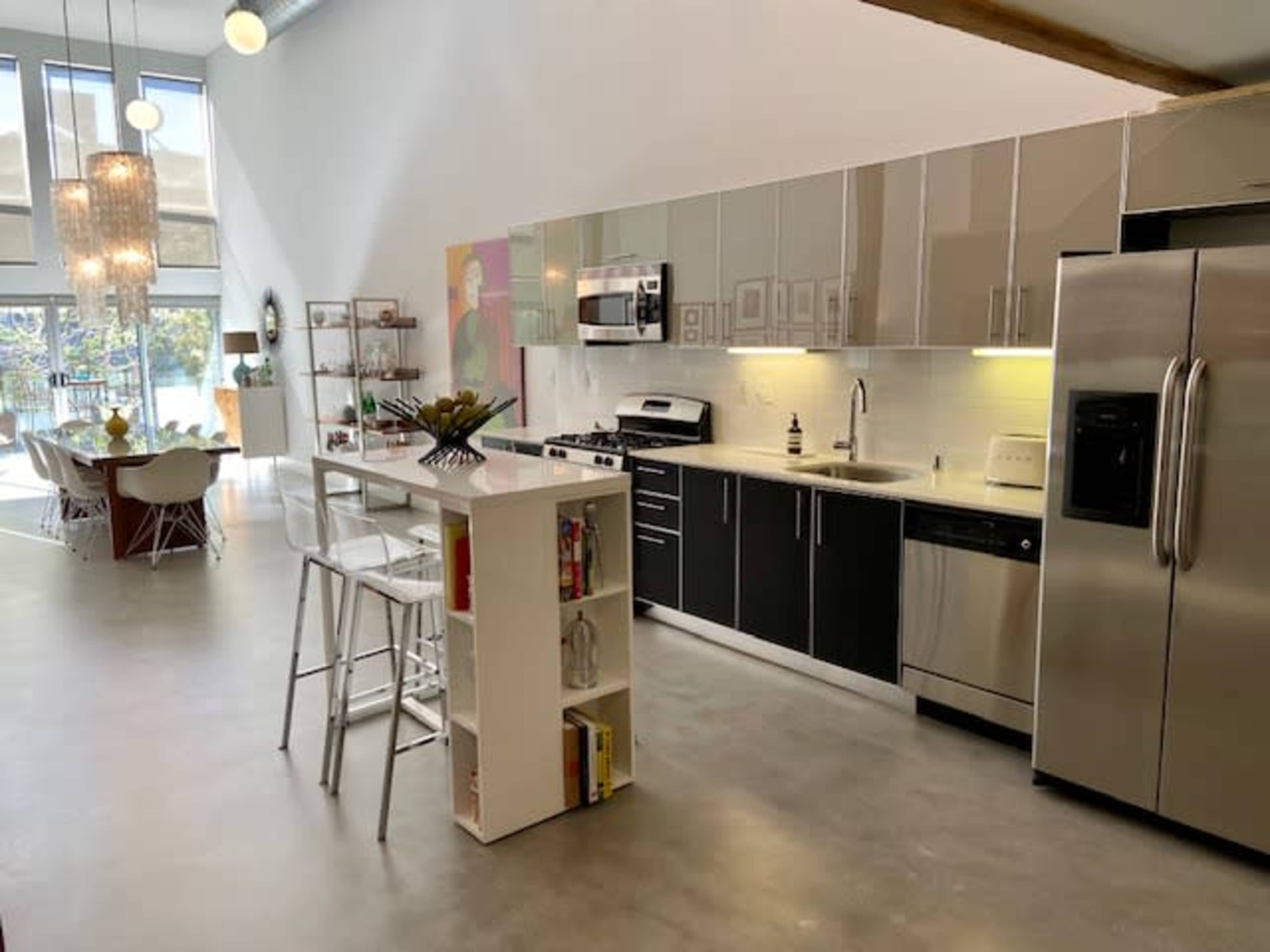 A modern kitchen with sleek cabinets, stainless steel appliances, and a dining area featuring a round table and white chairs.