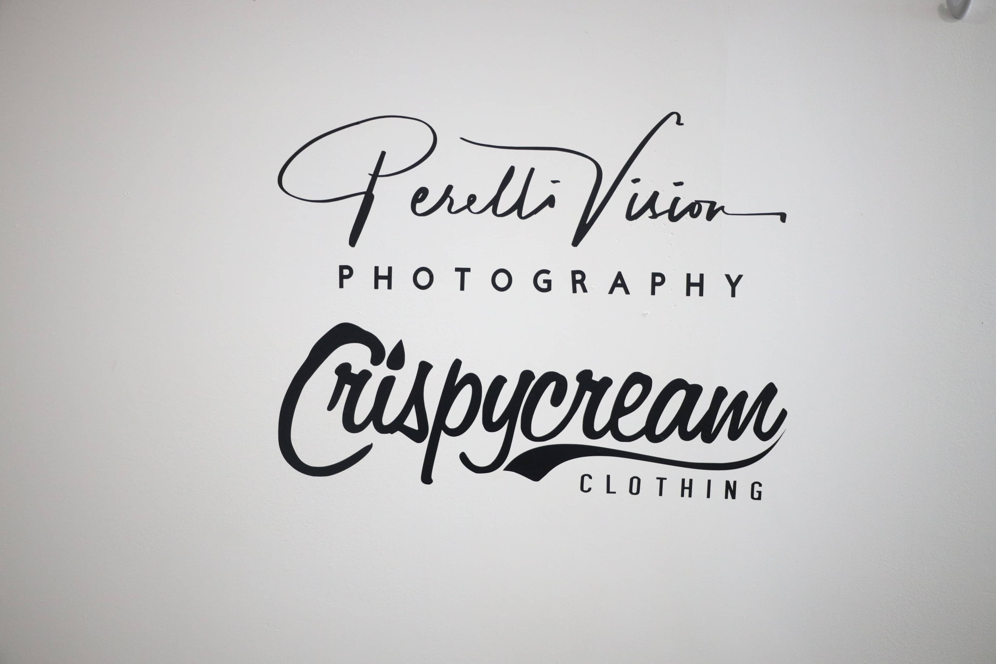 The image shows a wall with two business names: "Perelli Vision Photography" and "Crispycream Clothing" displayed in artistic fonts.
