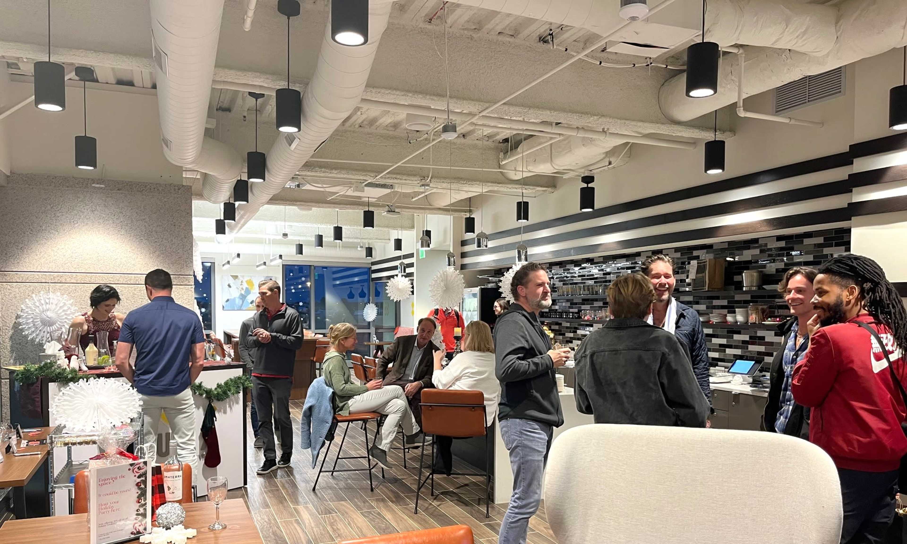 A group of people socializes in a modern, brightly-lit interior setting with stylish furnishings and decorative elements.