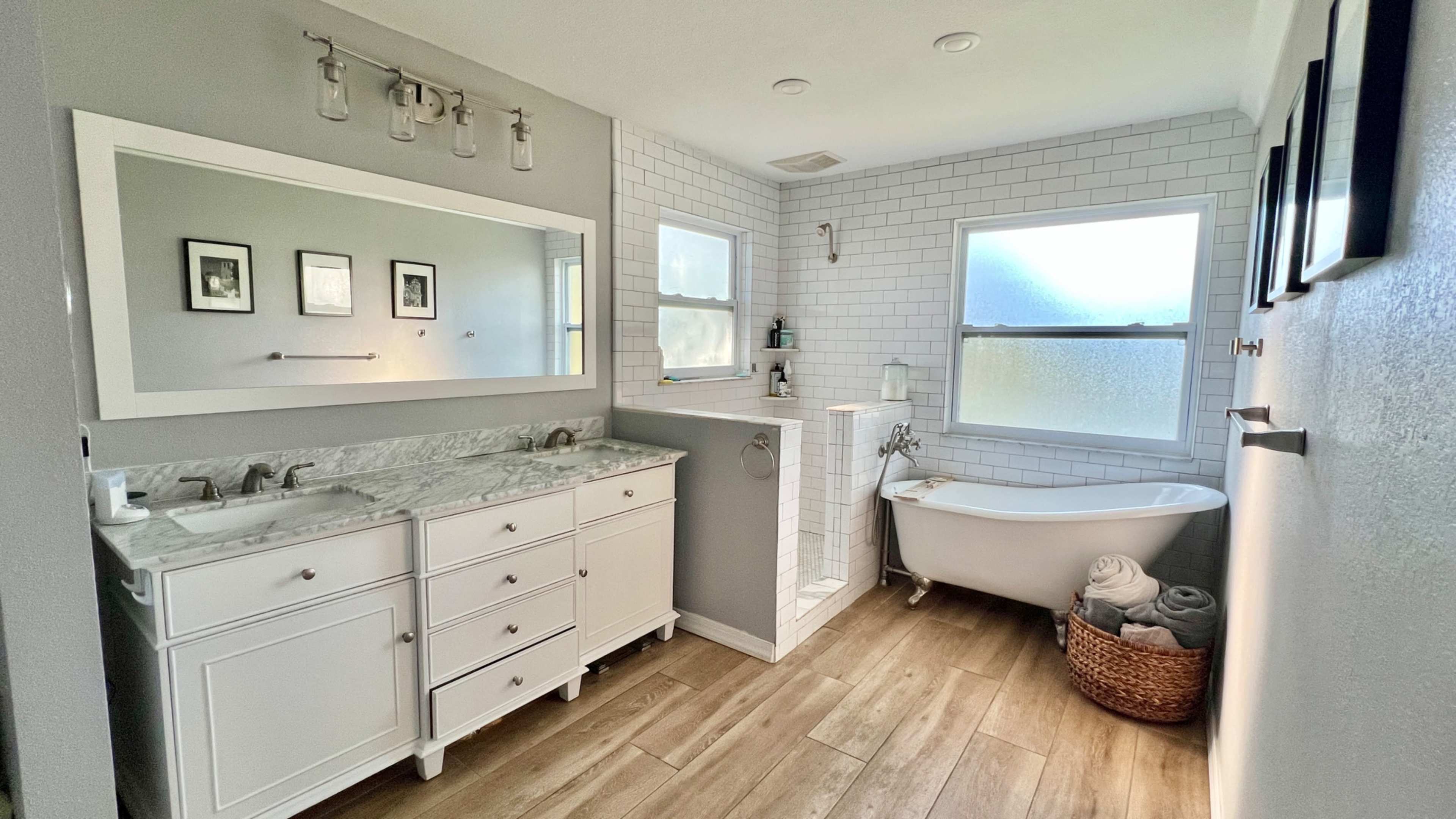The image shows a modern bathroom featuring a double sink vanity, a freestanding bathtub, and a tiled shower with a glass enclosure.