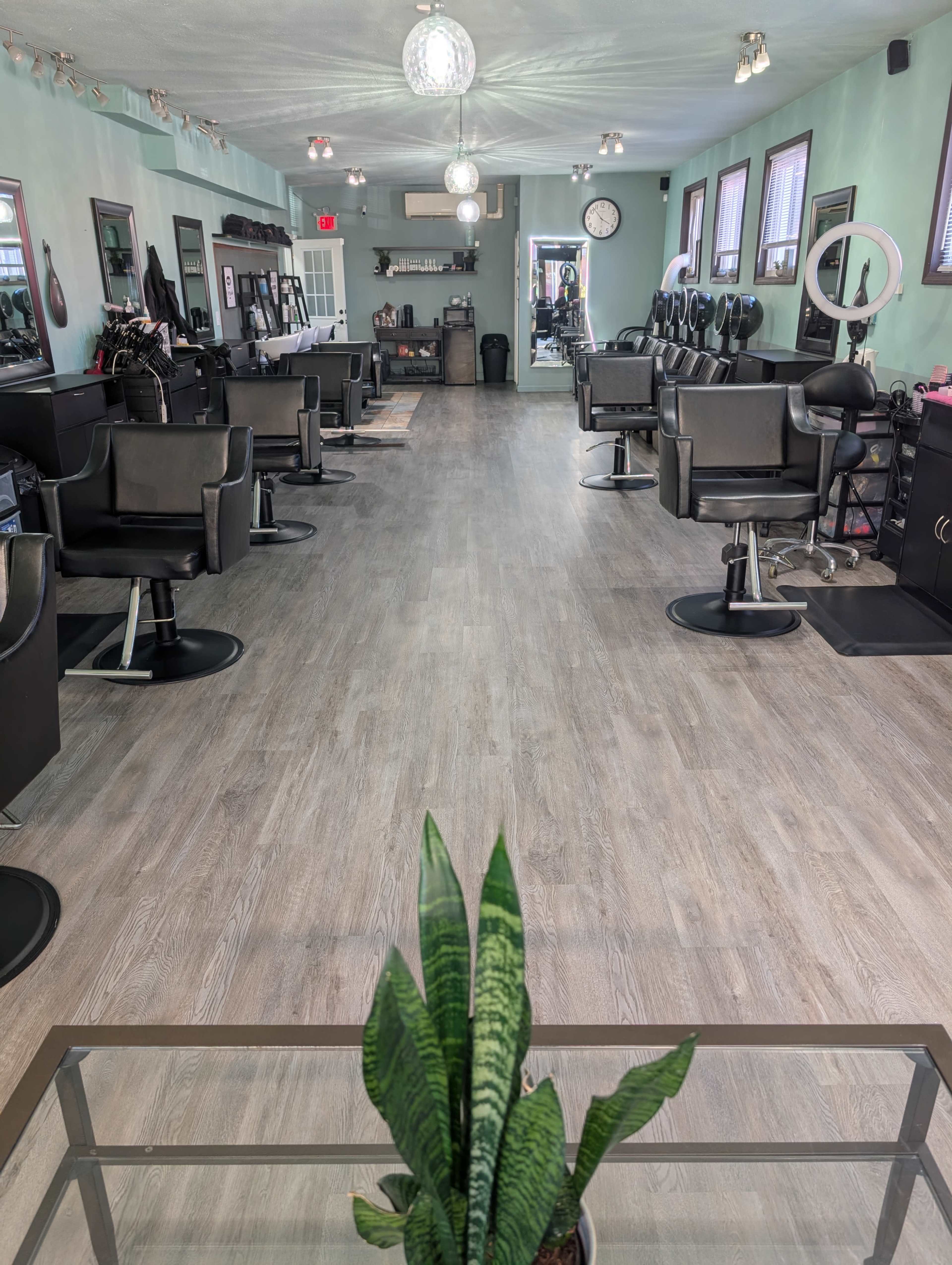 The image shows a spacious hair salon with several styling stations and a clean, modern interior layout.