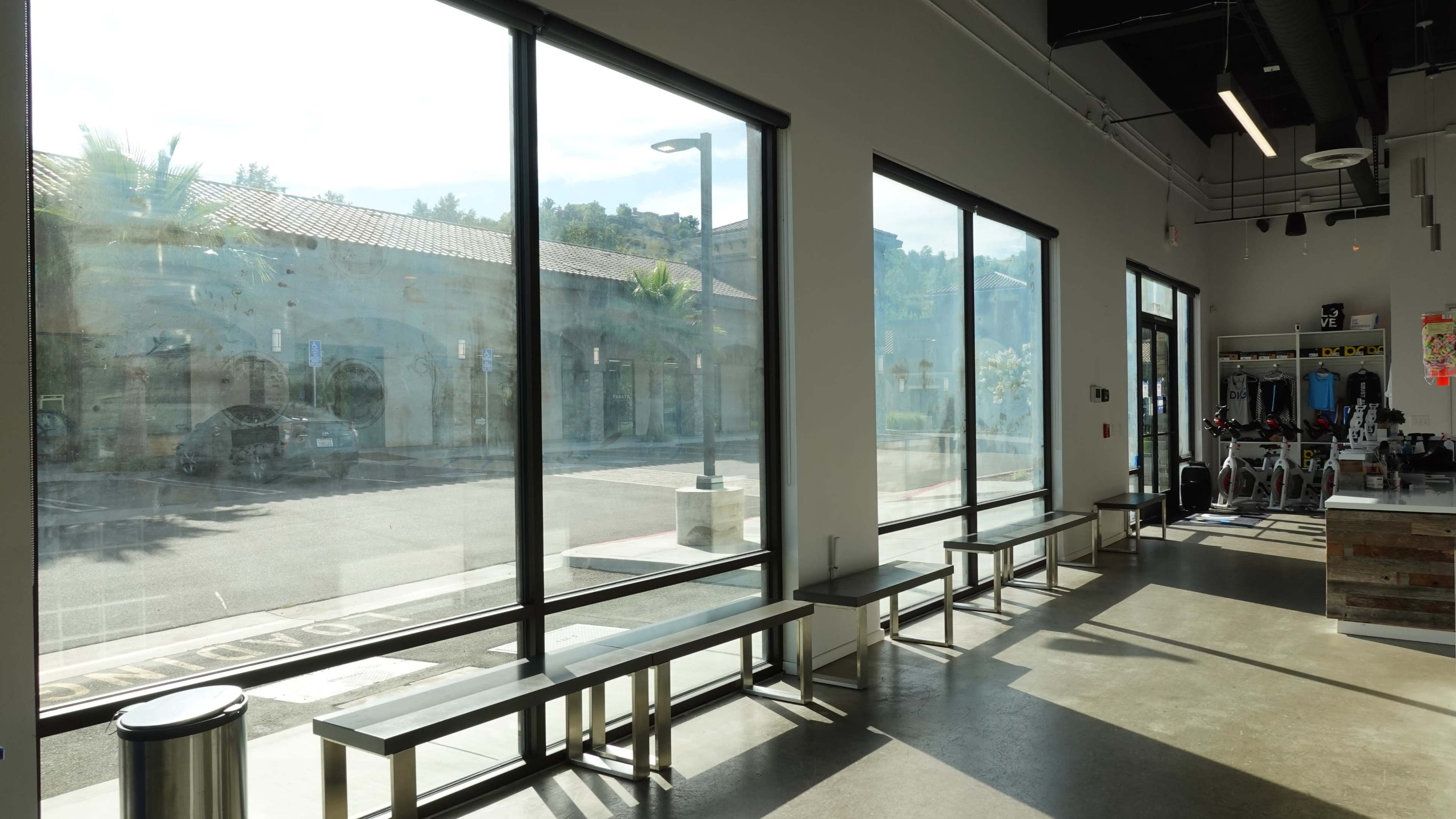 A bright interior space with large windows that overlook an outdoor area and feature multiple benches.