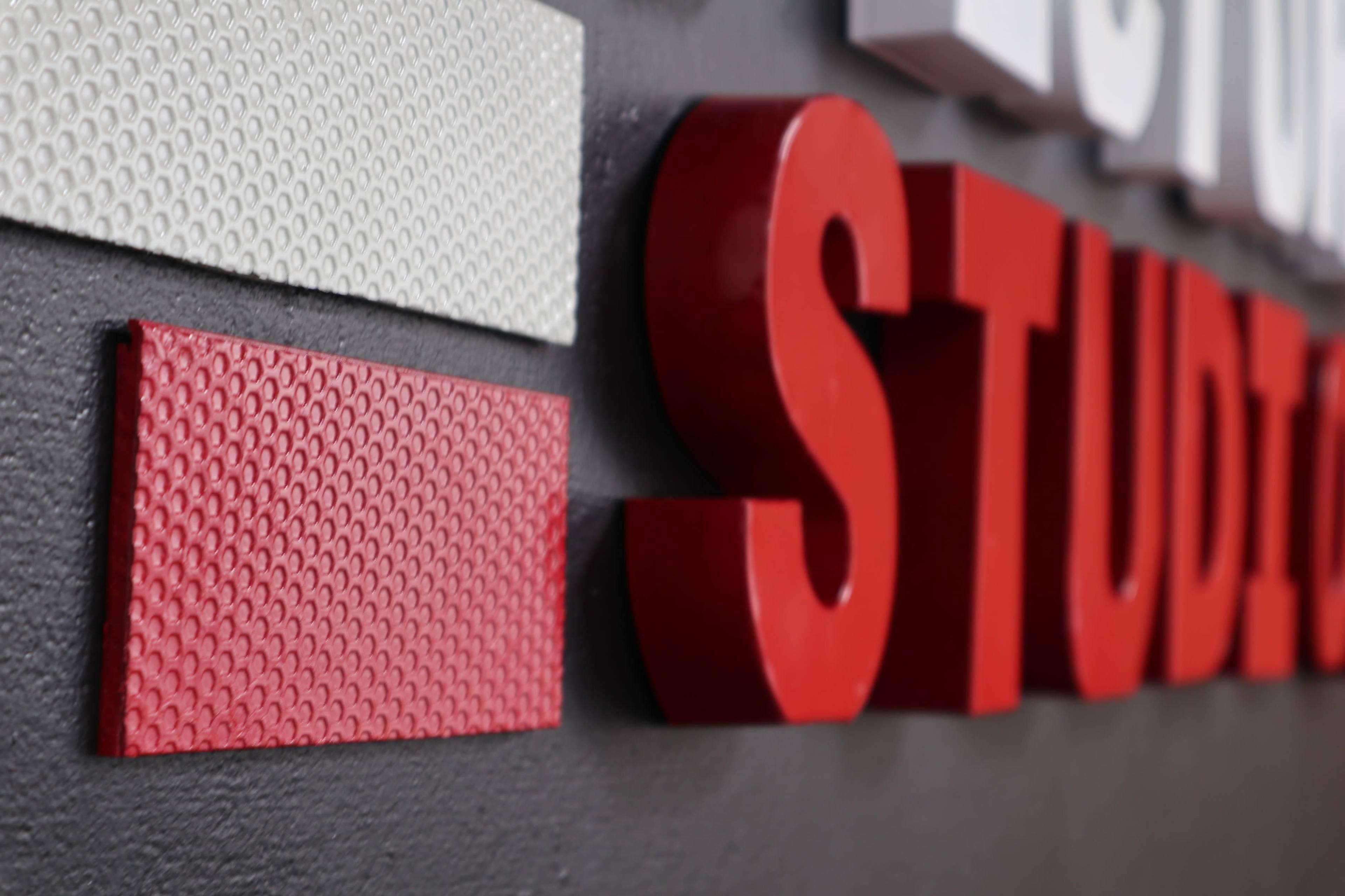 A textured wall featuring red and white letters spelling "STUDIO" alongside a patterned red rectangle.