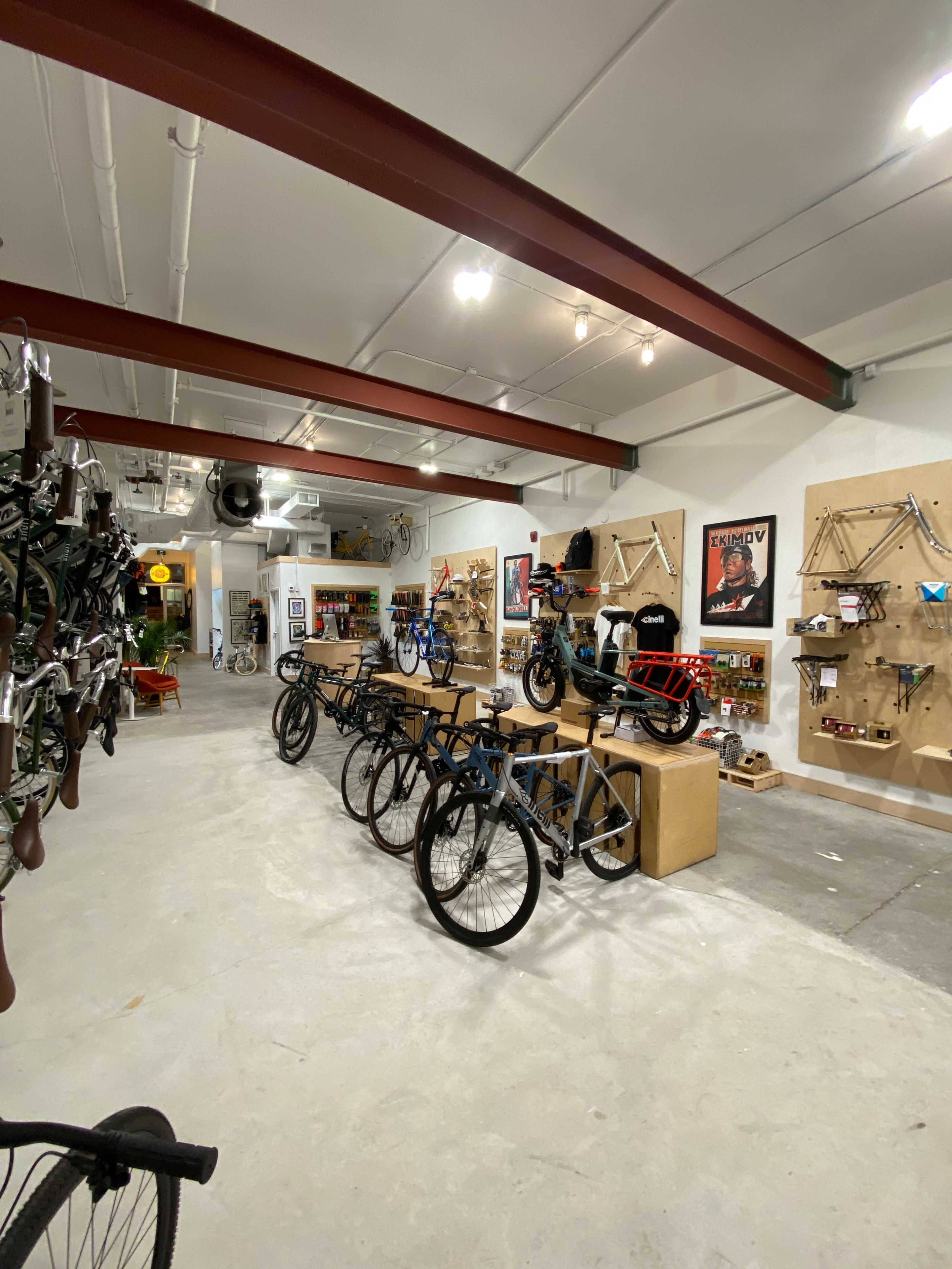 The image shows a bike shop featuring several bicycles on display and a variety of bike accessories mounted on the walls.