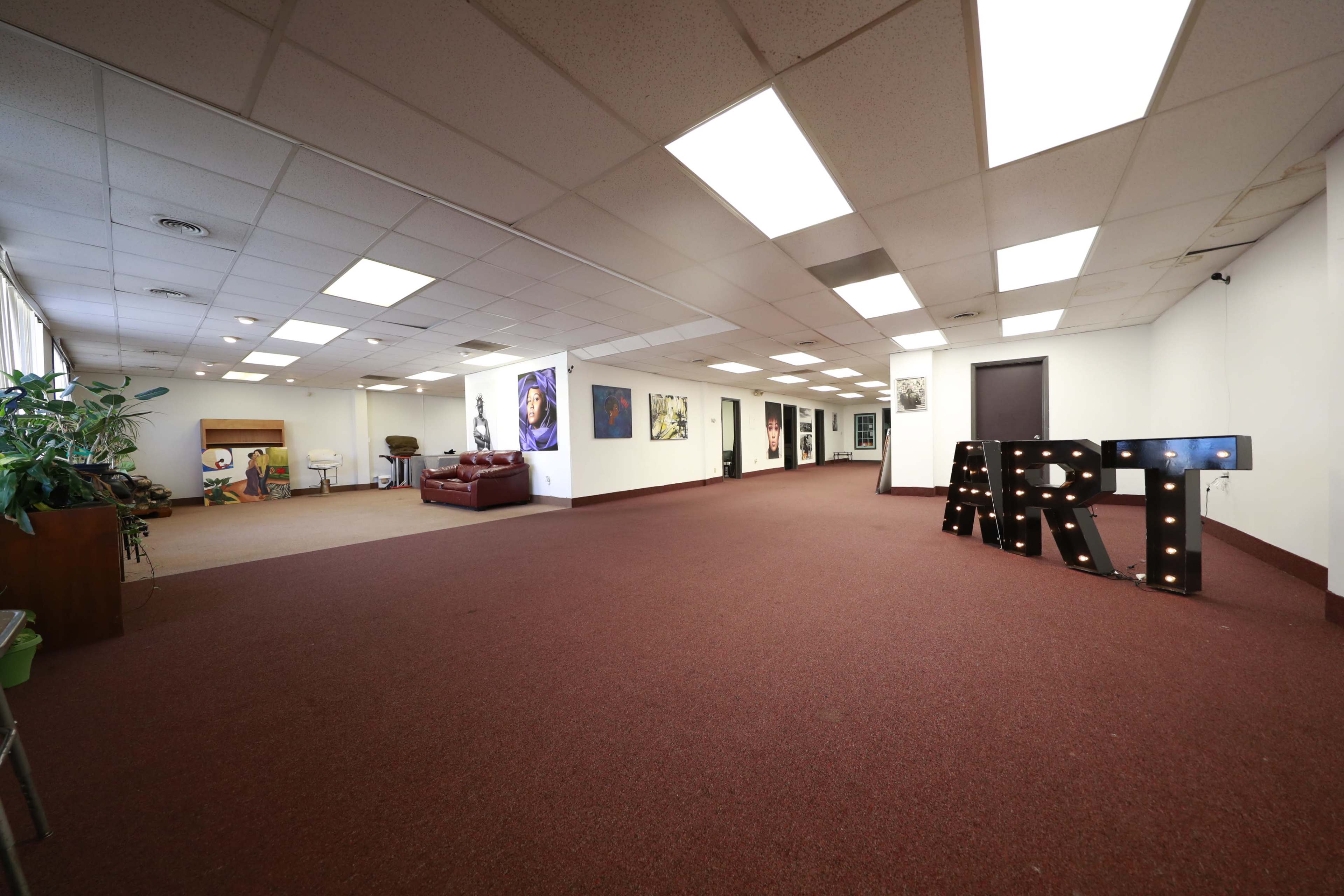 A spacious art gallery with artworks displayed on the walls and a decorative sign spelling "ART" made of lights in the foreground.
