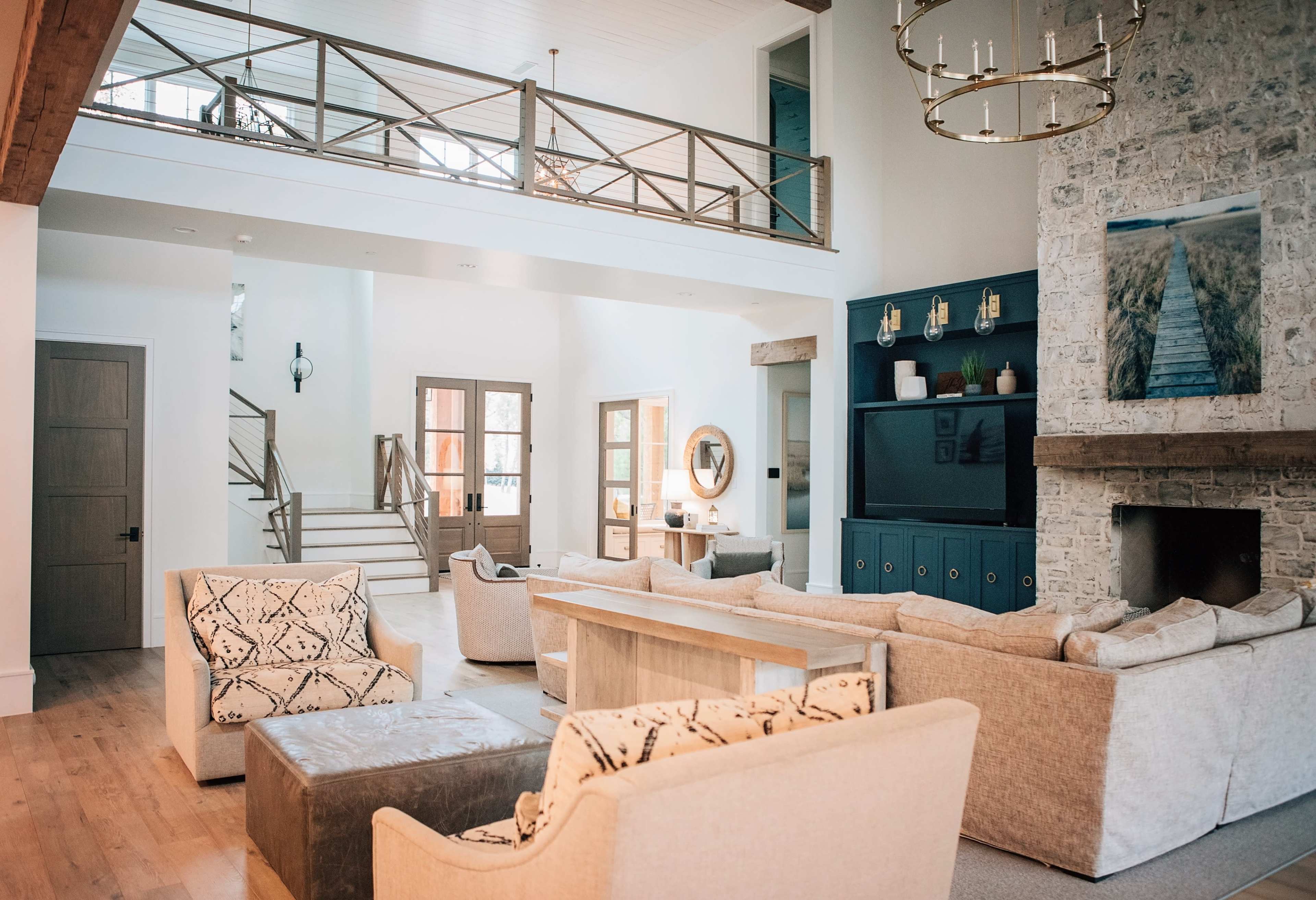 A spacious living room features a stone fireplace, large windows, and a mix of seating arrangements, including sofas and armchairs.