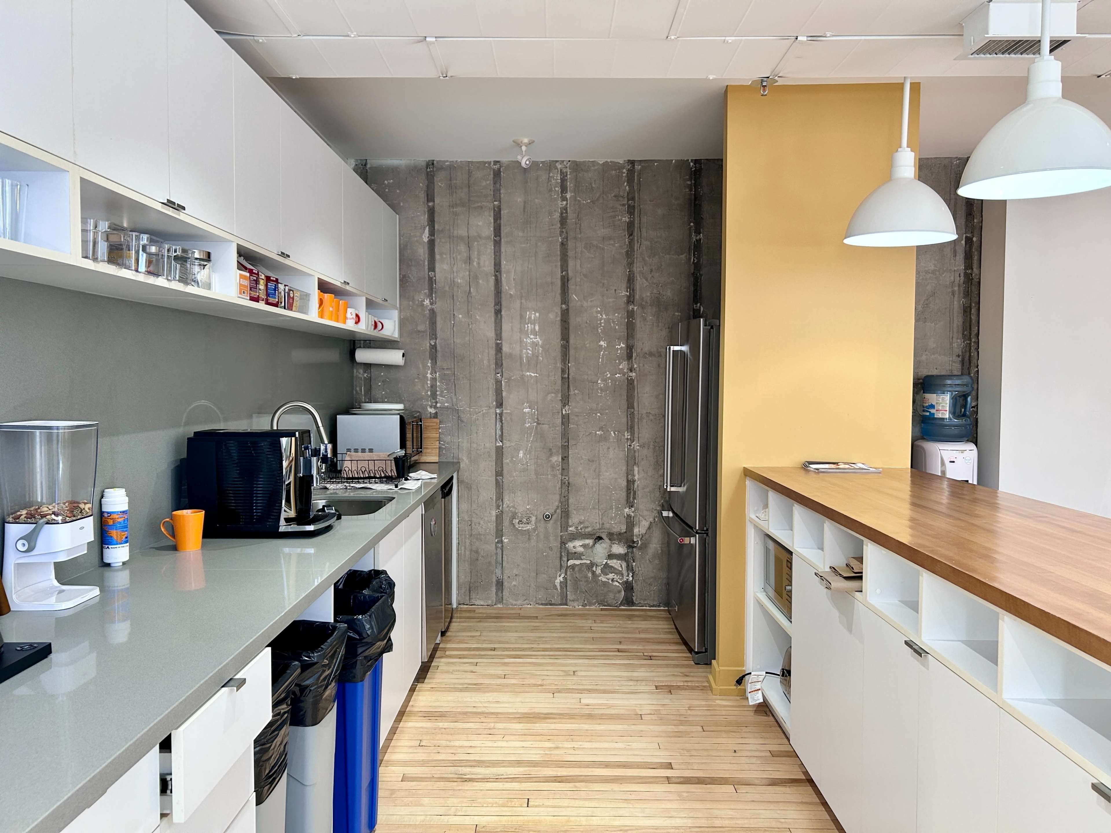 The kitchen features a gray and white color scheme with modern cabinetry, a wooden countertop, and an exposed concrete wall.