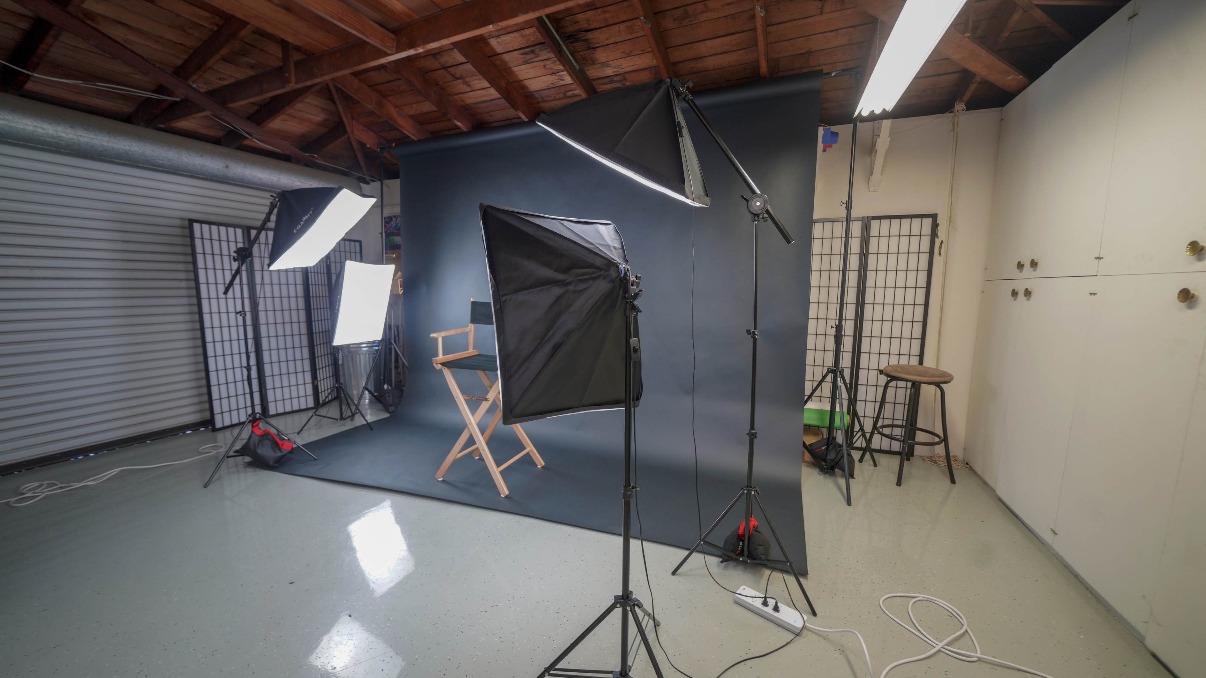 A photography studio setup with a backdrop, lights, and a director's chair.