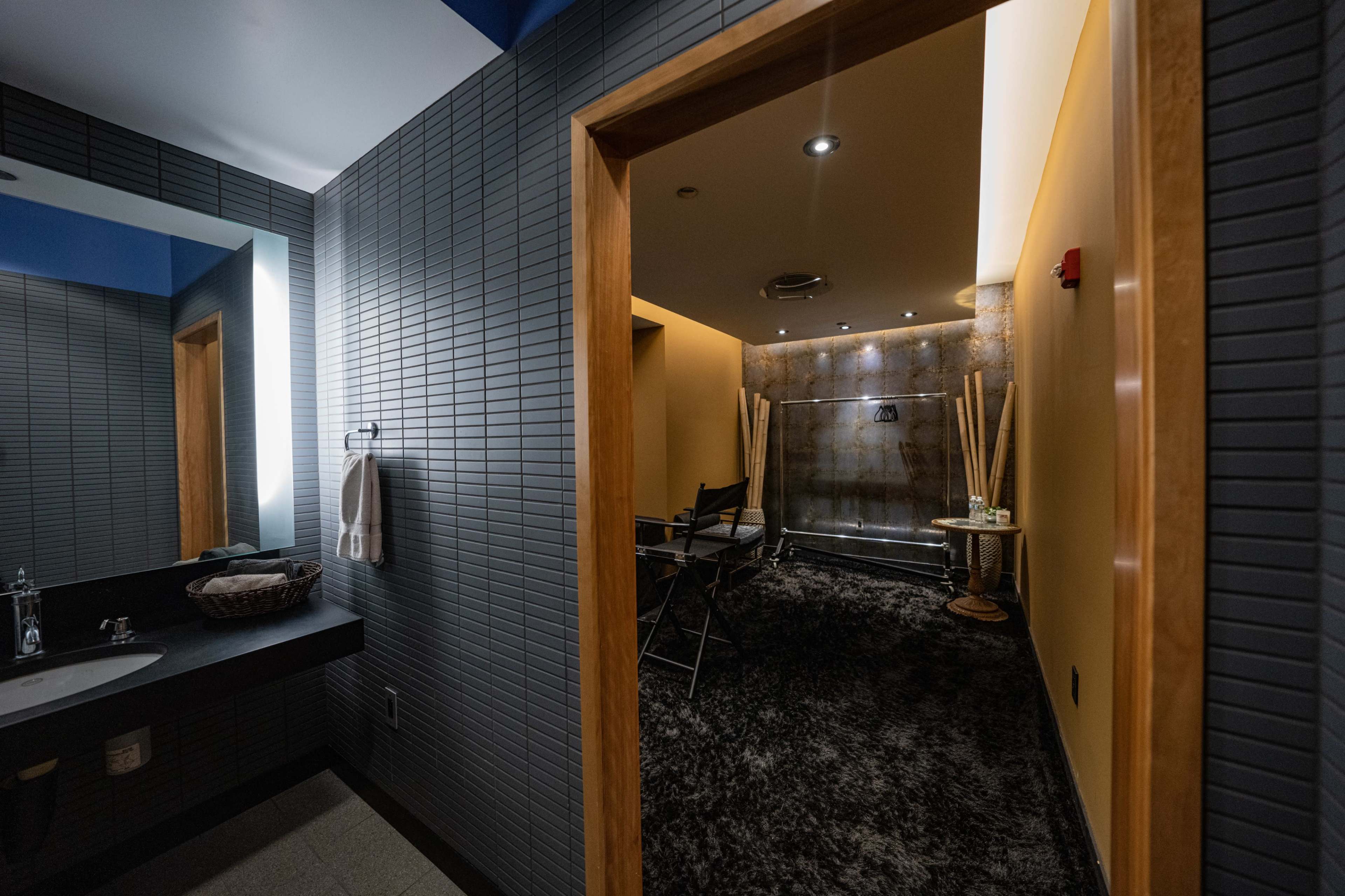 A modern bathroom with a separate shower area and dark tile walls.